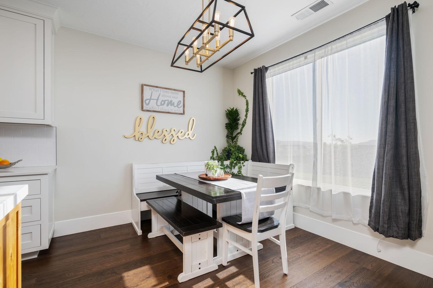 Bright dining area featuring a prominent window, dark wood-finish flooring, and white cabinetry