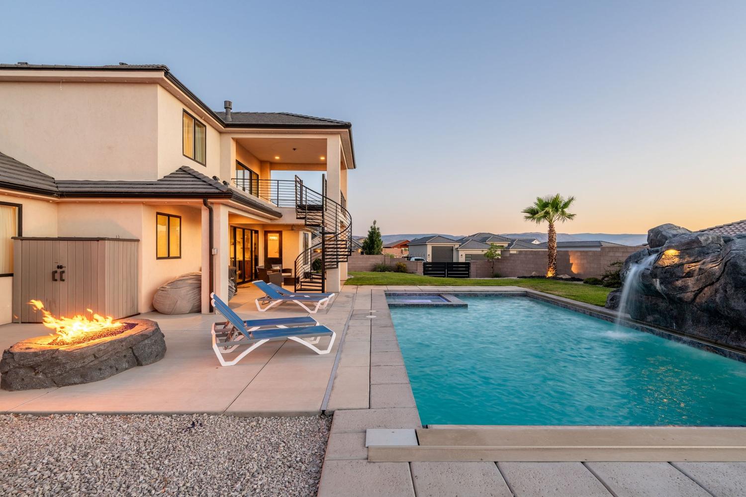 Outdoor entertainment area featuring a rectangular pool with an integrated spa and rock waterfall