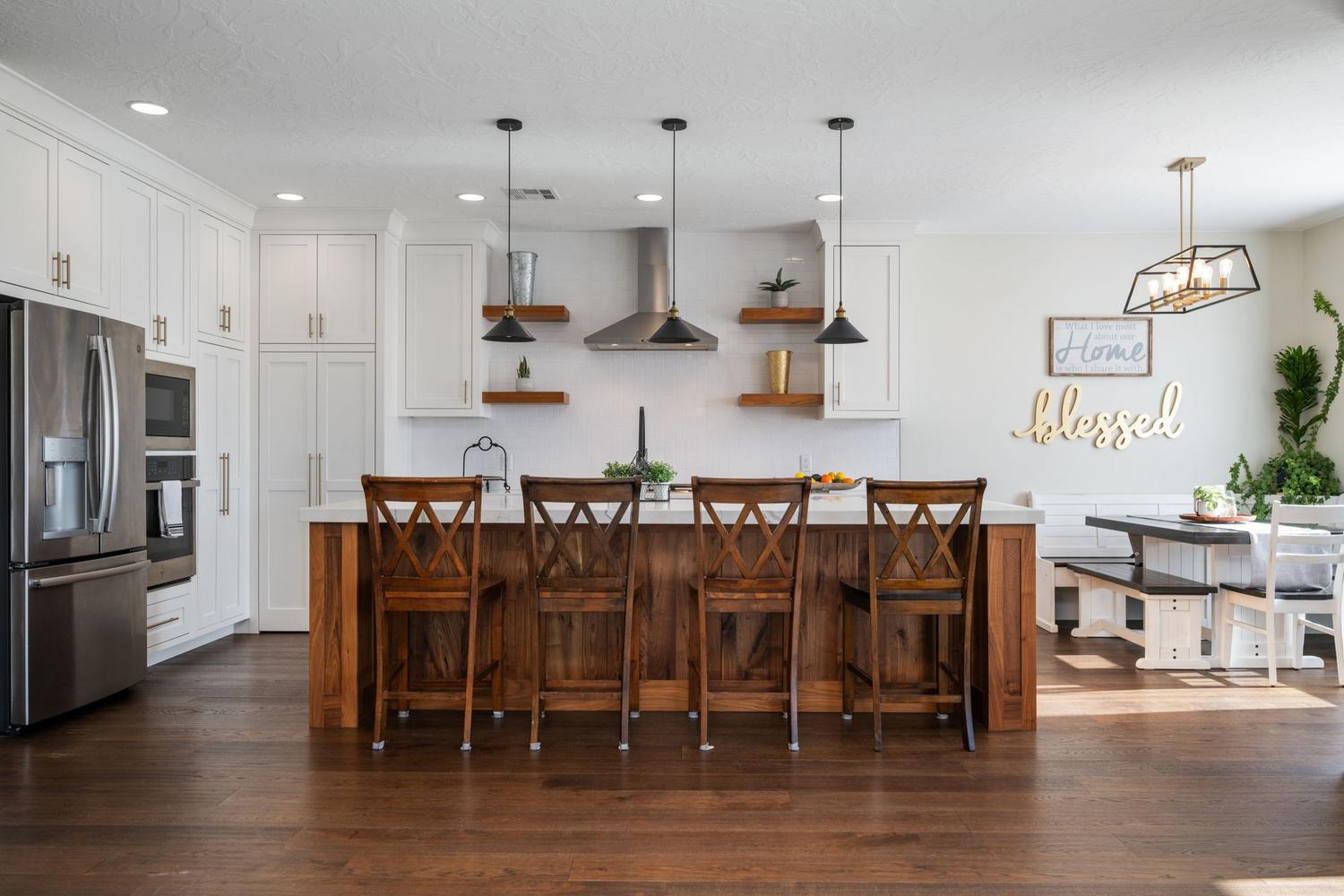 Open-concept kitchen featuring white shaker cabinetry, stainless steel appliances, and a wood-finish island with a light-toned countertop