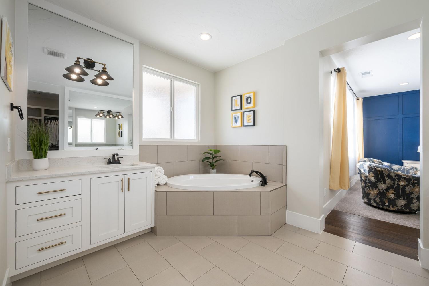 Bathroom featuring a built-in corner soaking tub, white vanity with a light-toned countertop, and tile flooring