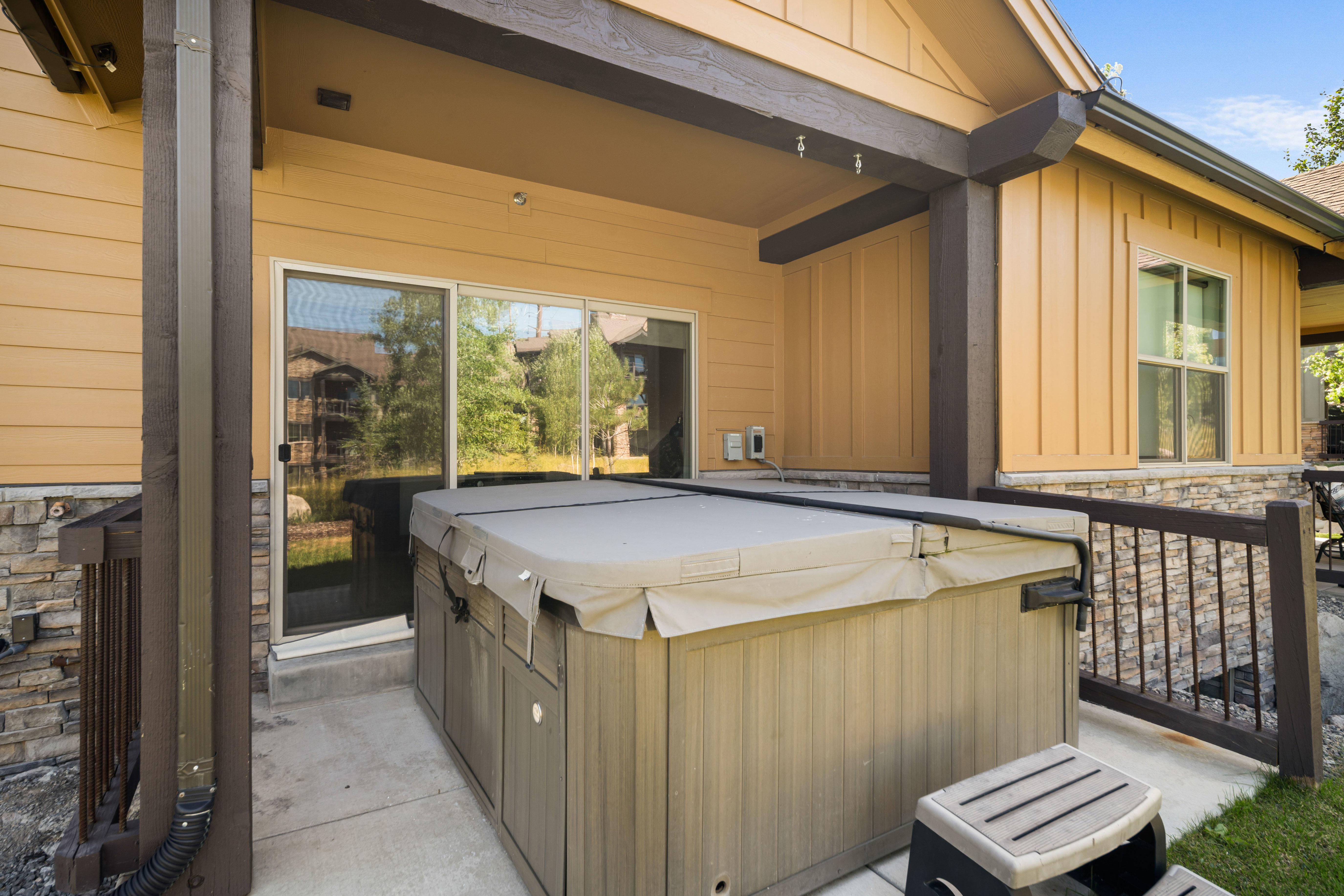 Covered patio featuring a hot tub, concrete flooring, and stone facade accents
