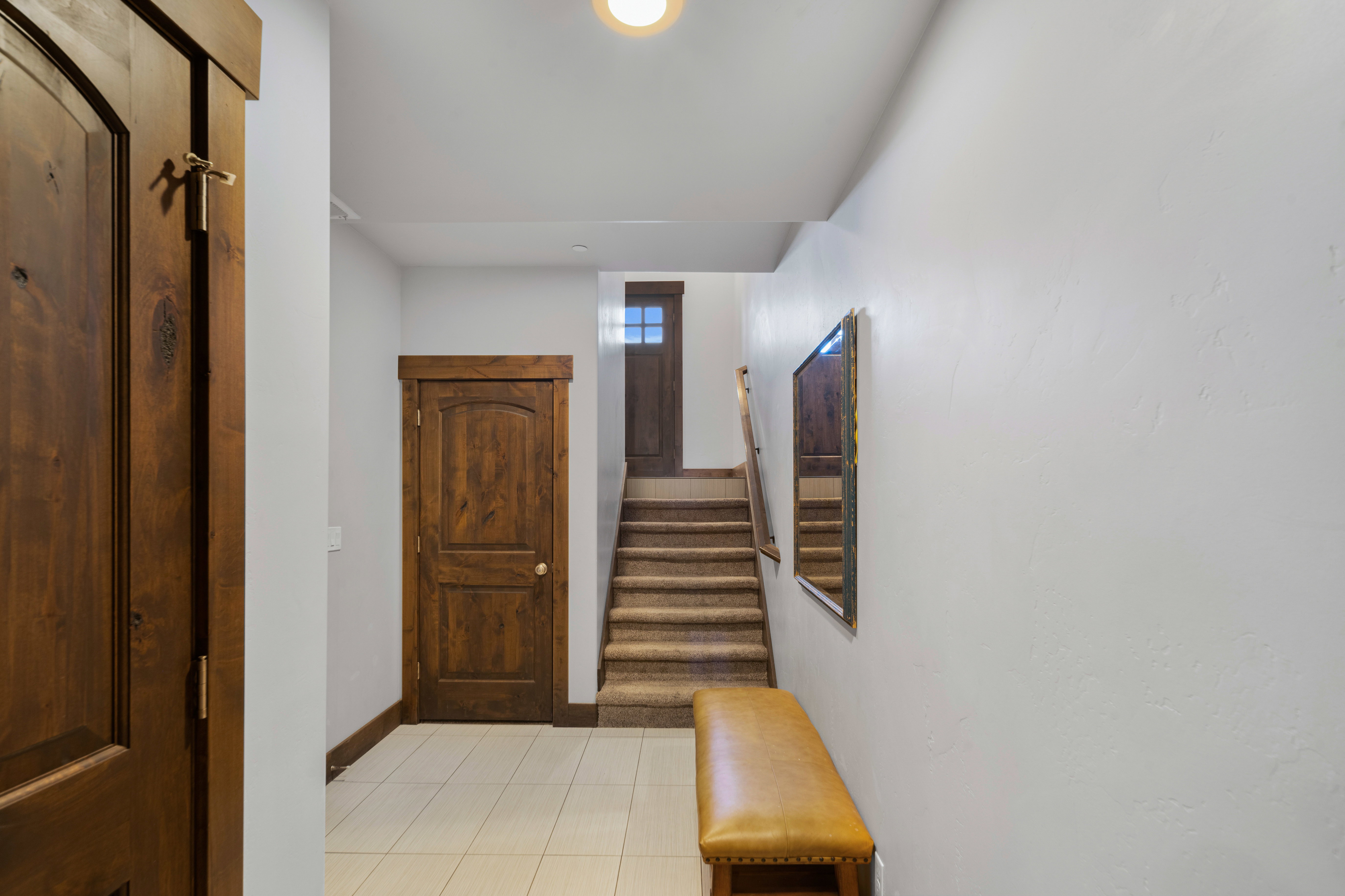 Entryway featuring warm-toned wood doors and trim, neutral wall finishes, and light-toned tile flooring