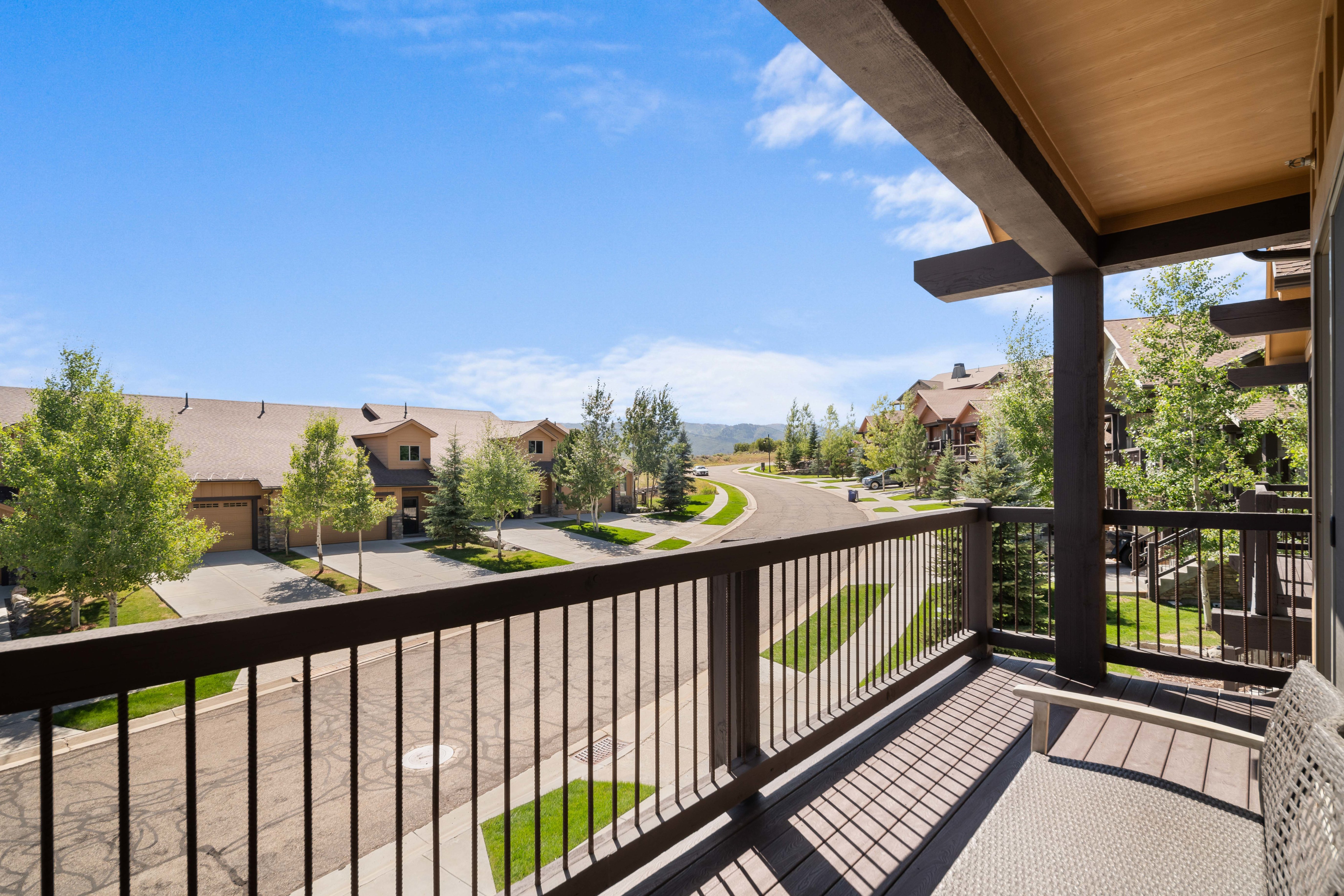 Covered outdoor balcony with composite decking, dark wood railings, and exposed beam ceiling