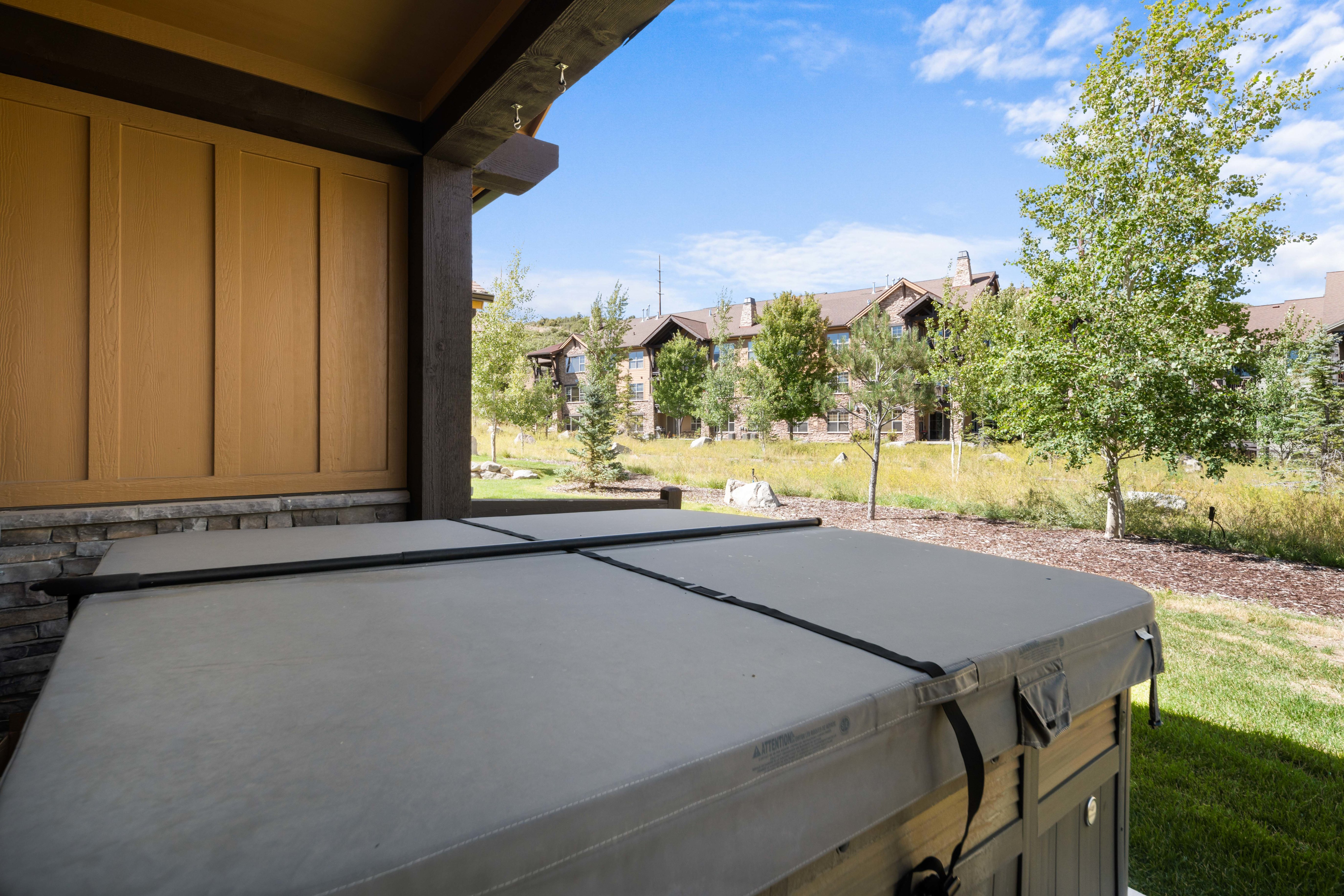 Covered patio with a built-in hot tub, featuring a stacked stone wall and wood paneling
