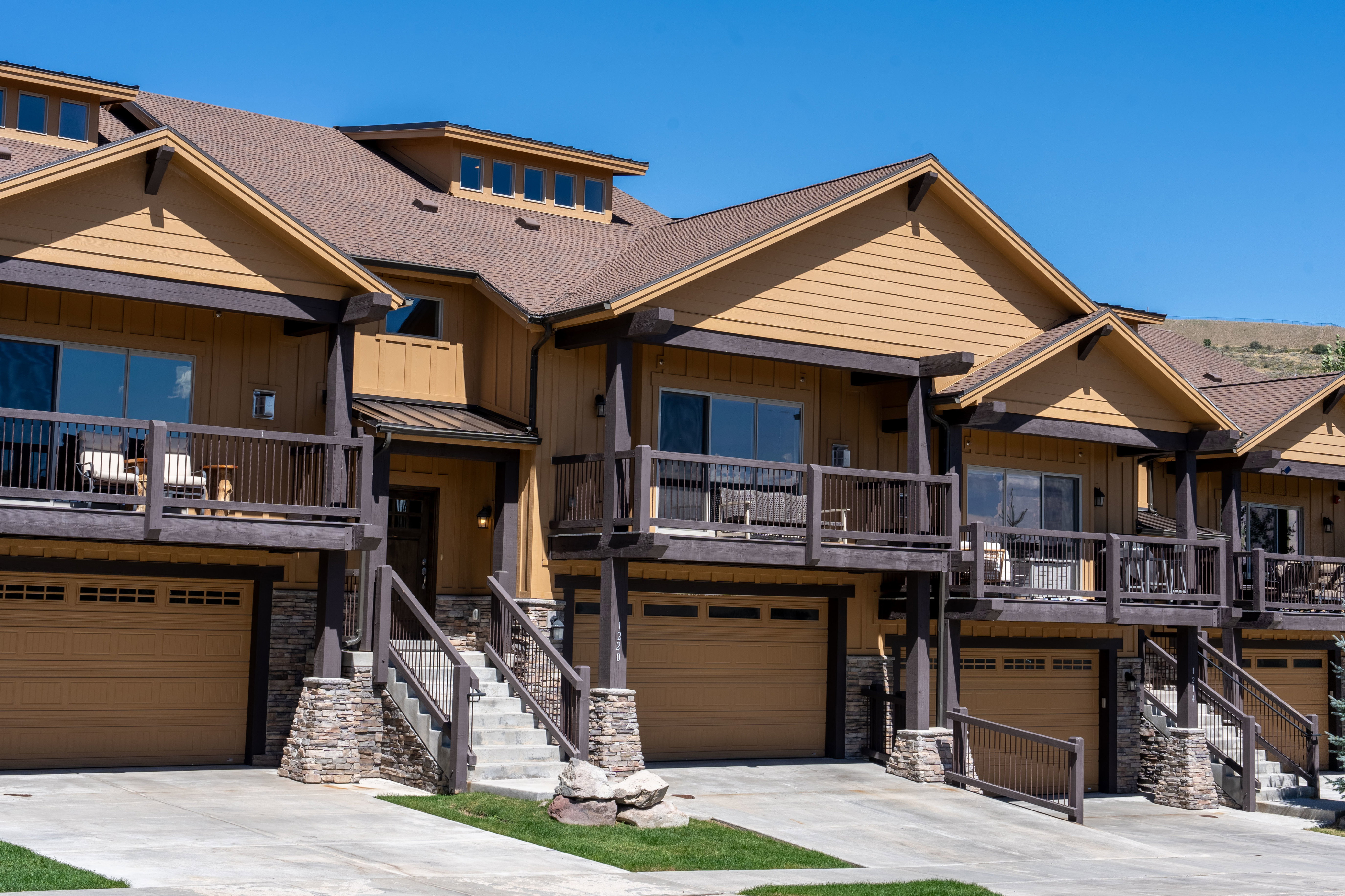 Townhome exterior featuring horizontal siding, stone accents, and multiple private balconies