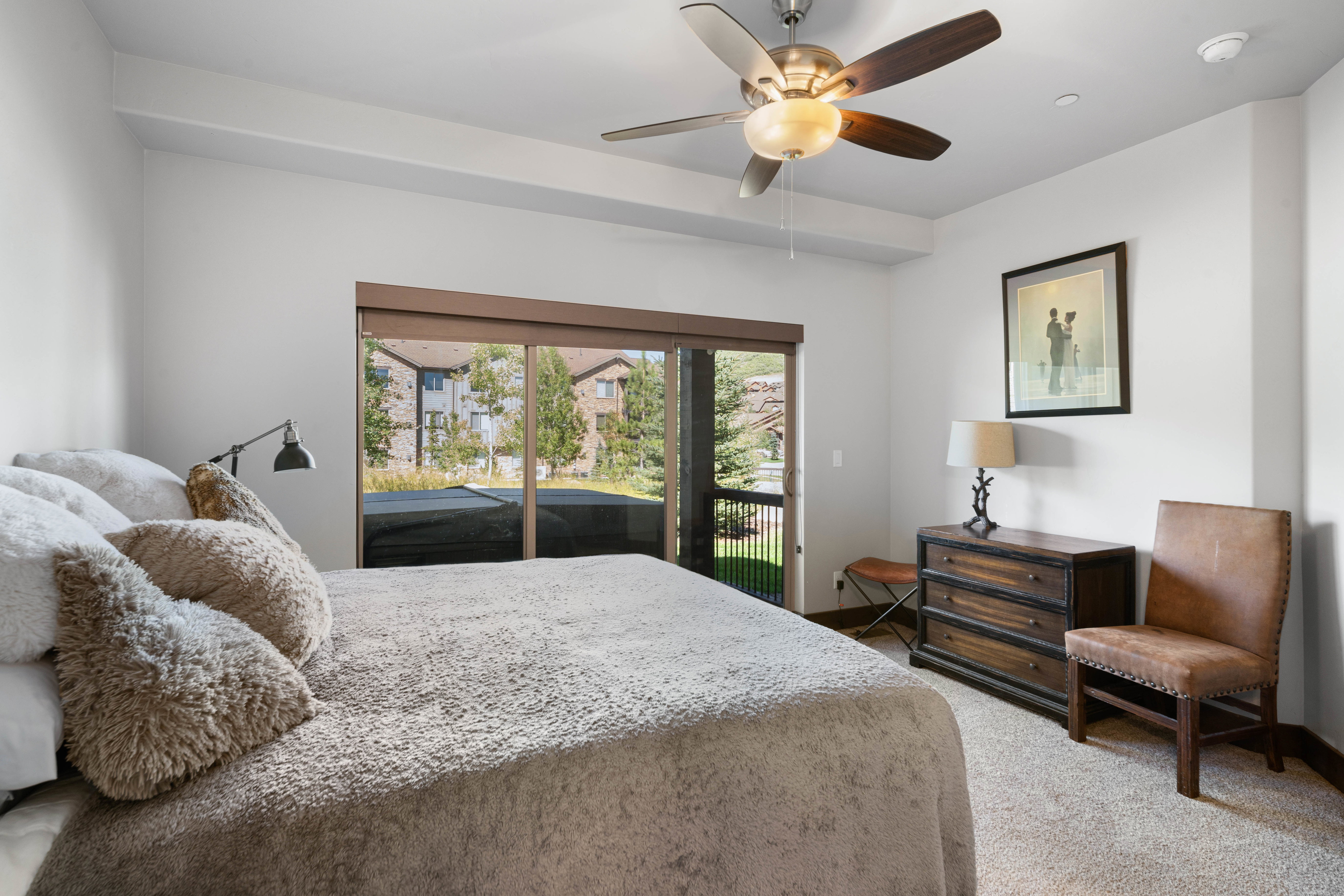 Spacious room featuring a glass sliding door to a balcony, a ceiling fan with integrated lighting, and neutral carpeting