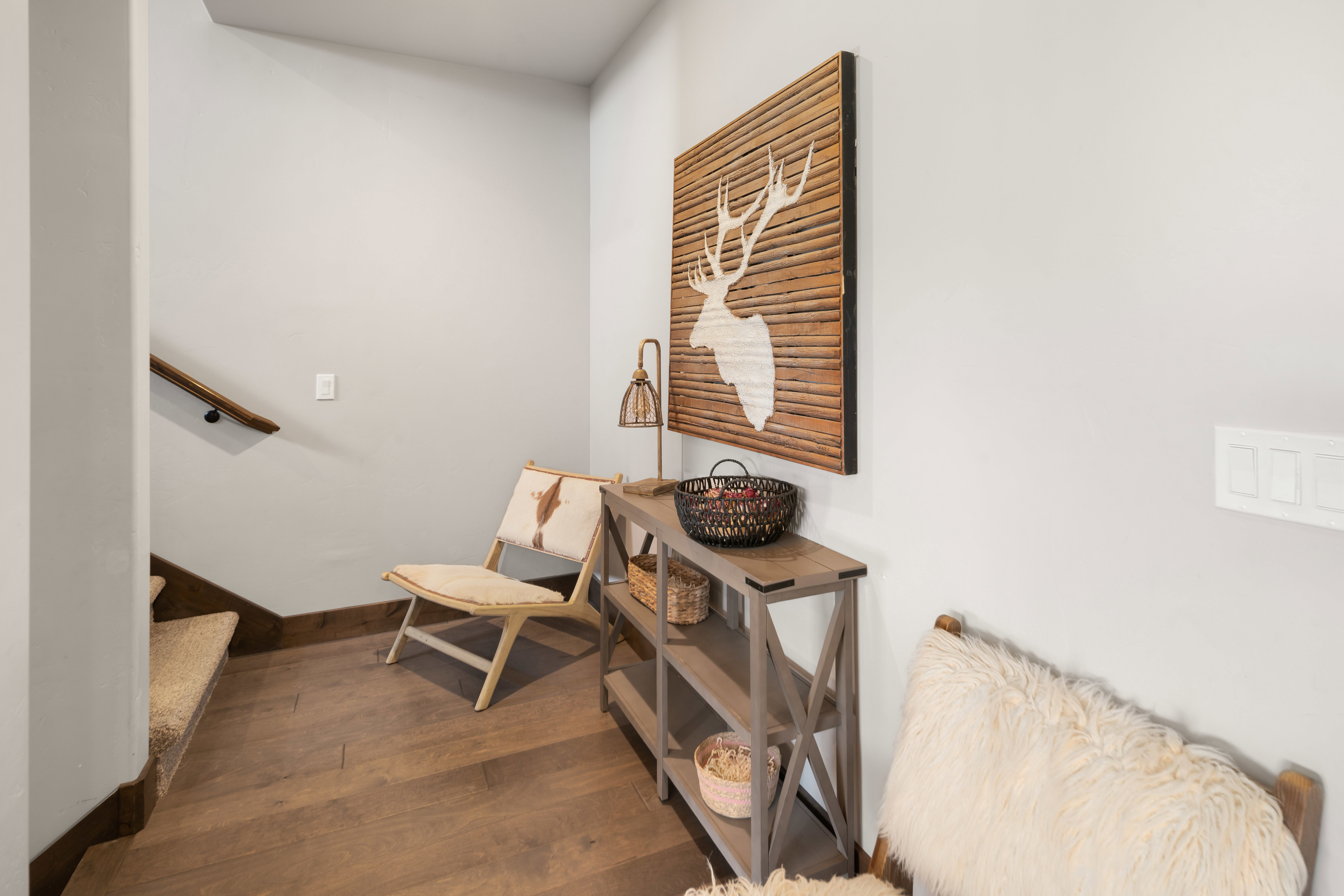 Hardwood-finish flooring extending from the hallway, complemented by a carpeted staircase with a wood handrail