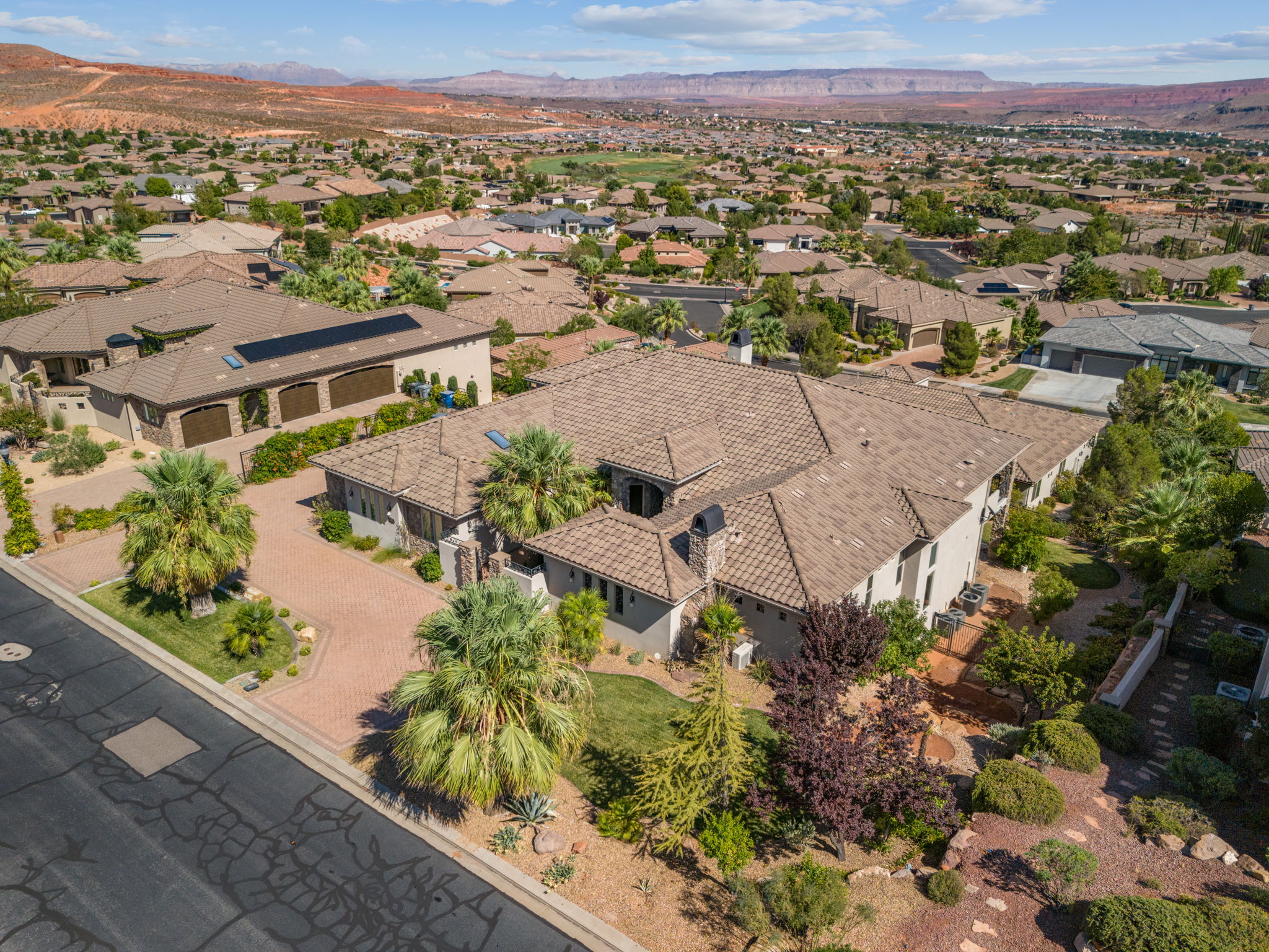 Aerial perspective showcasing a sprawling property with a tiled roof and a paver driveway