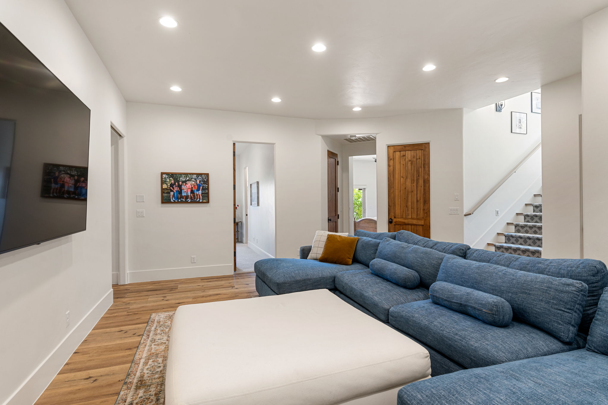 Spacious living area featuring light wood-finish flooring, recessed lighting, and white baseboards