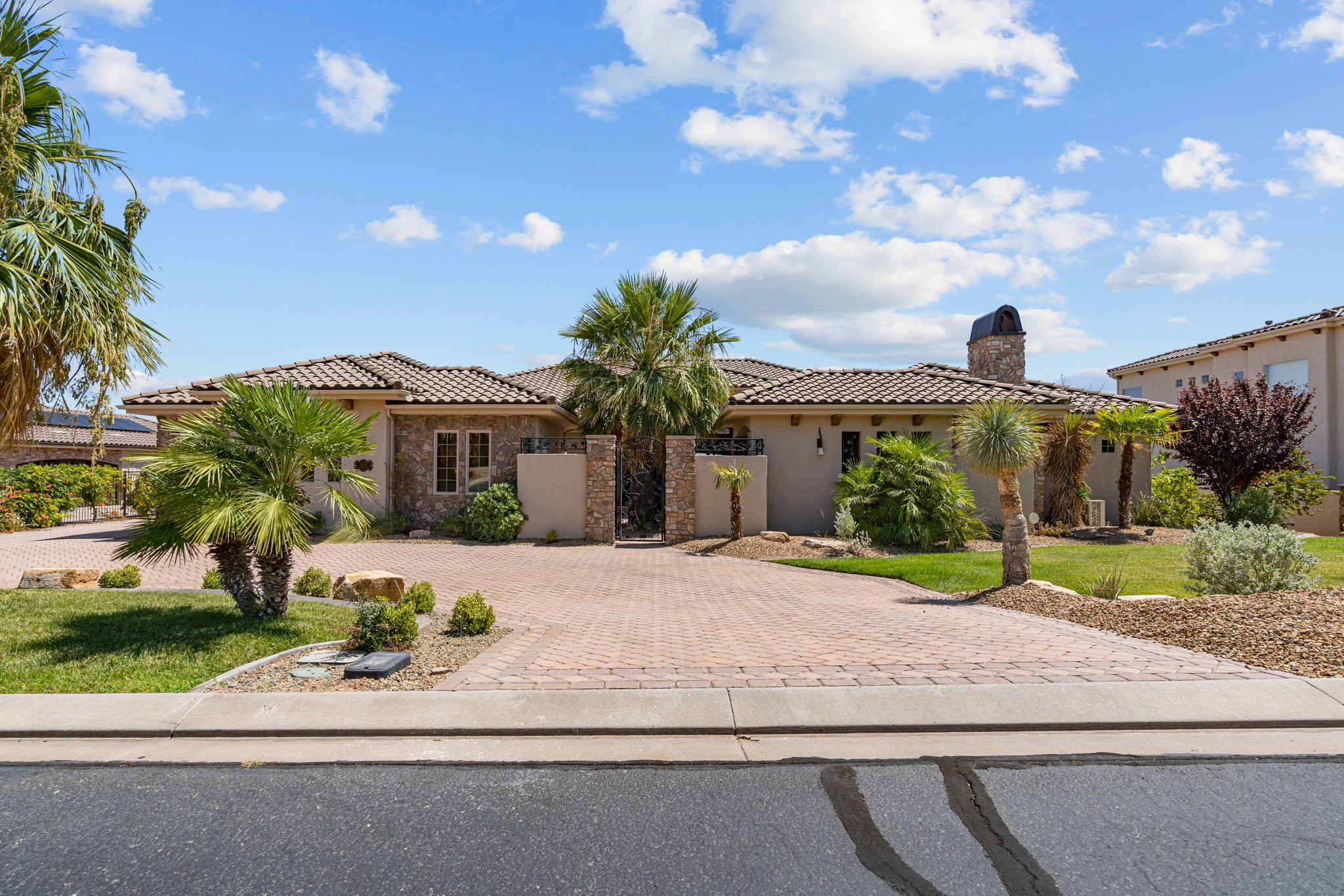 Mediterranean-style single-story residence featuring a tile roof, stone facade accents, and a paver driveway