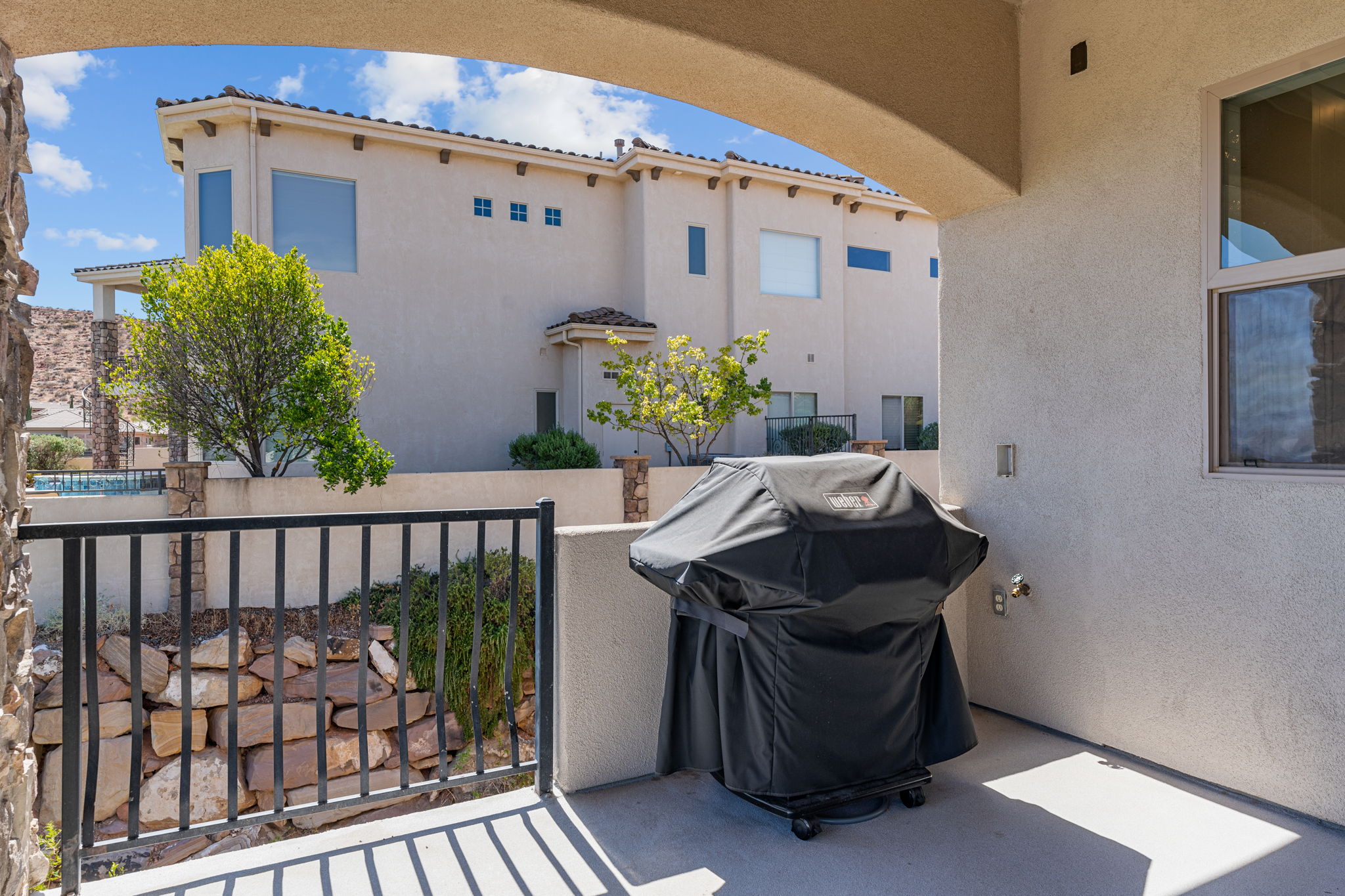 Covered patio area with a textured stucco exterior, an arched entryway, and a metal railing