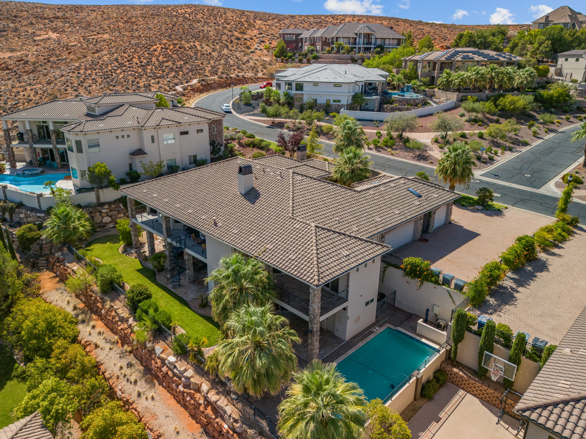 Multi-level residence featuring a tile roof, multiple balconies, a covered pool, and a paved sport court