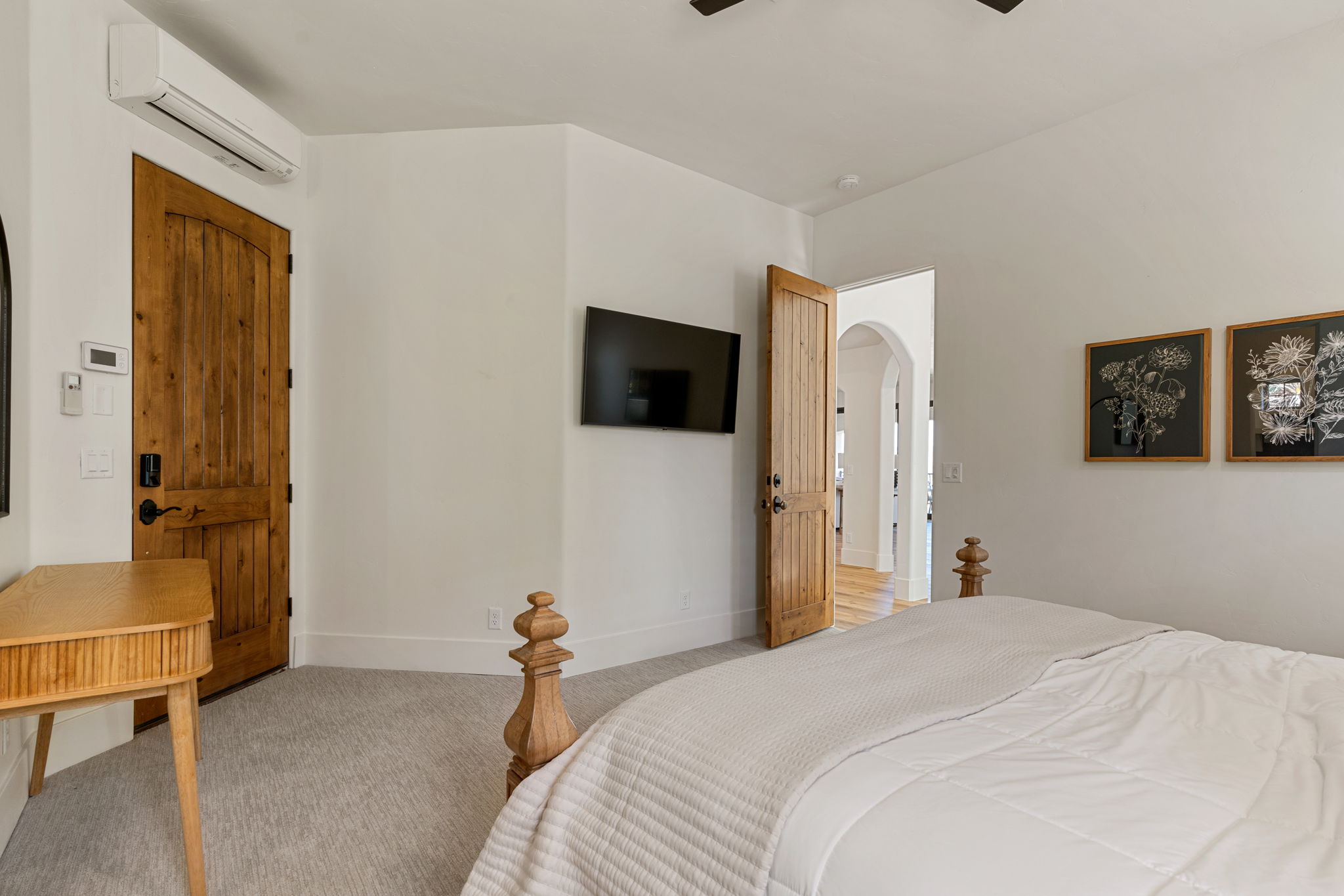 Carpeted room featuring a rustic wood-panel door, white baseboards, and a wall-mounted climate control unit