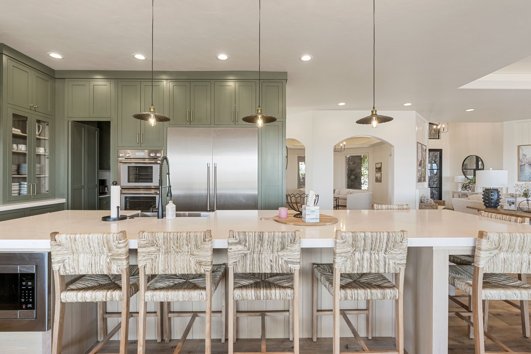 Spacious kitchen featuring a large central island with integrated microwave, abundant cabinetry, stainless steel refrigerator, and built-in double ovens
