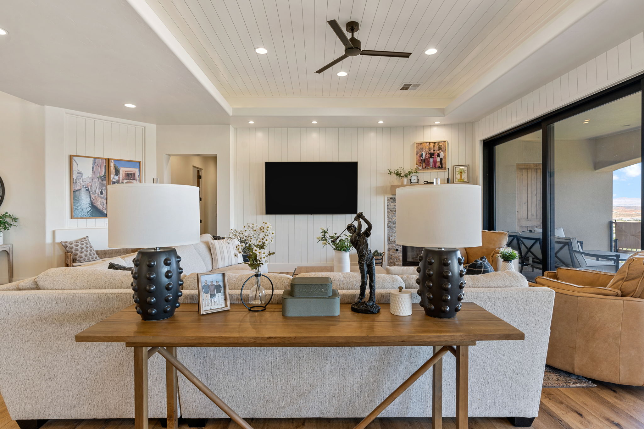 Spacious living area featuring a coffered shiplap ceiling, wood-finish flooring, a contemporary ceiling fan, and extensive sliding glass doors