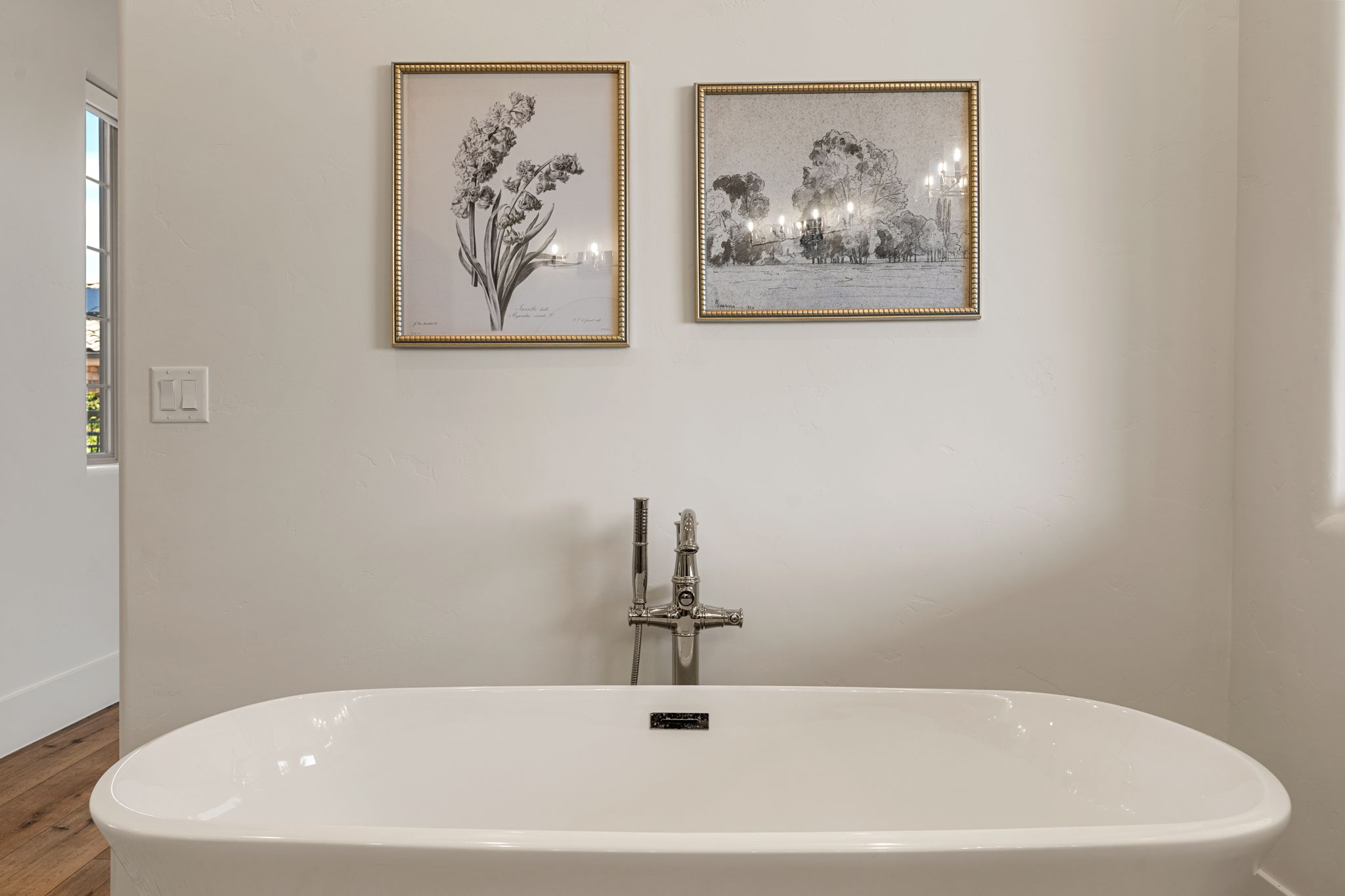 Freestanding soaking tub with a floor-mounted polished chrome faucet, set against a neutral wall