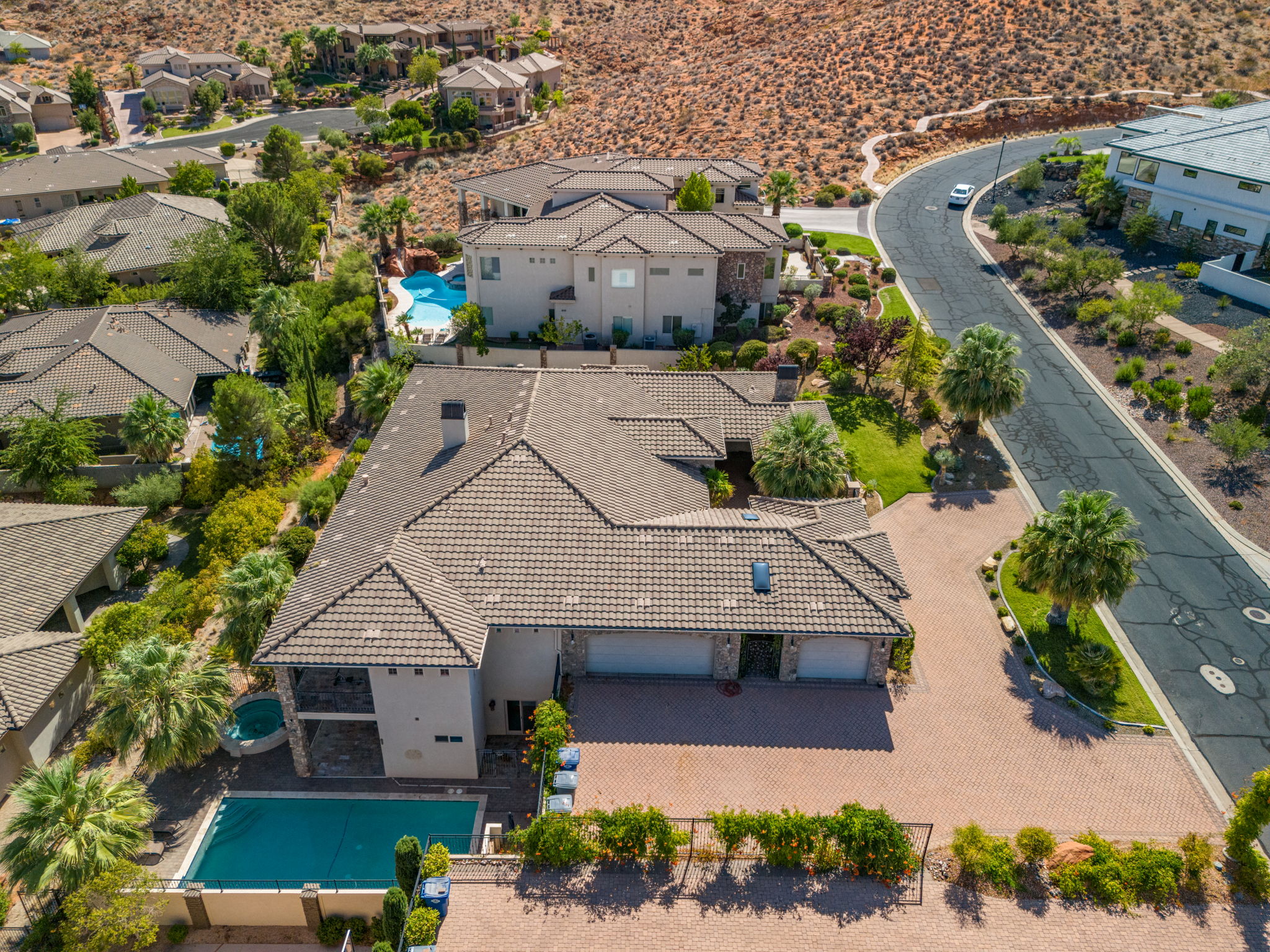 Expansive property featuring a multi-car garage, large driveway, mature landscaping, and a covered pool area with an attached spa