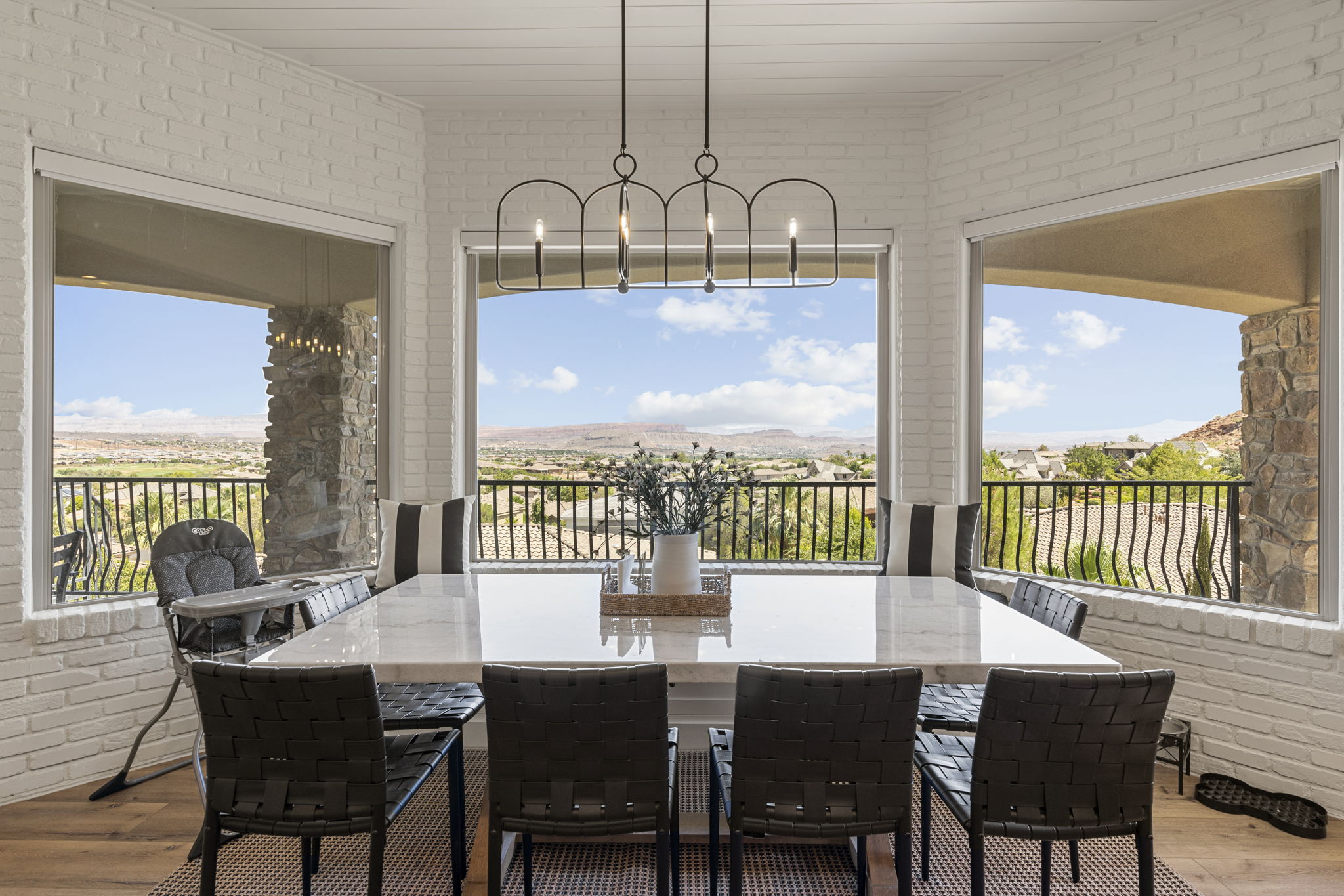 Dining area featuring a large rectangular table with a light-toned surface, surrounded by black chairs