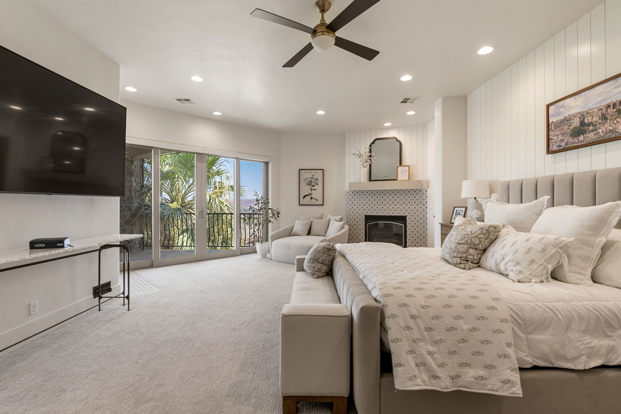 Spacious room with a ceiling fan and recessed lighting, featuring light-colored carpet flooring and a built-in electric fireplace with decorative tile surround