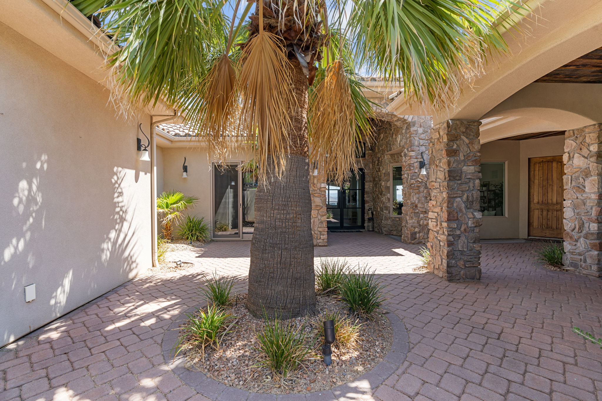 Paved entryway with a mature palm tree and low-maintenance landscaping