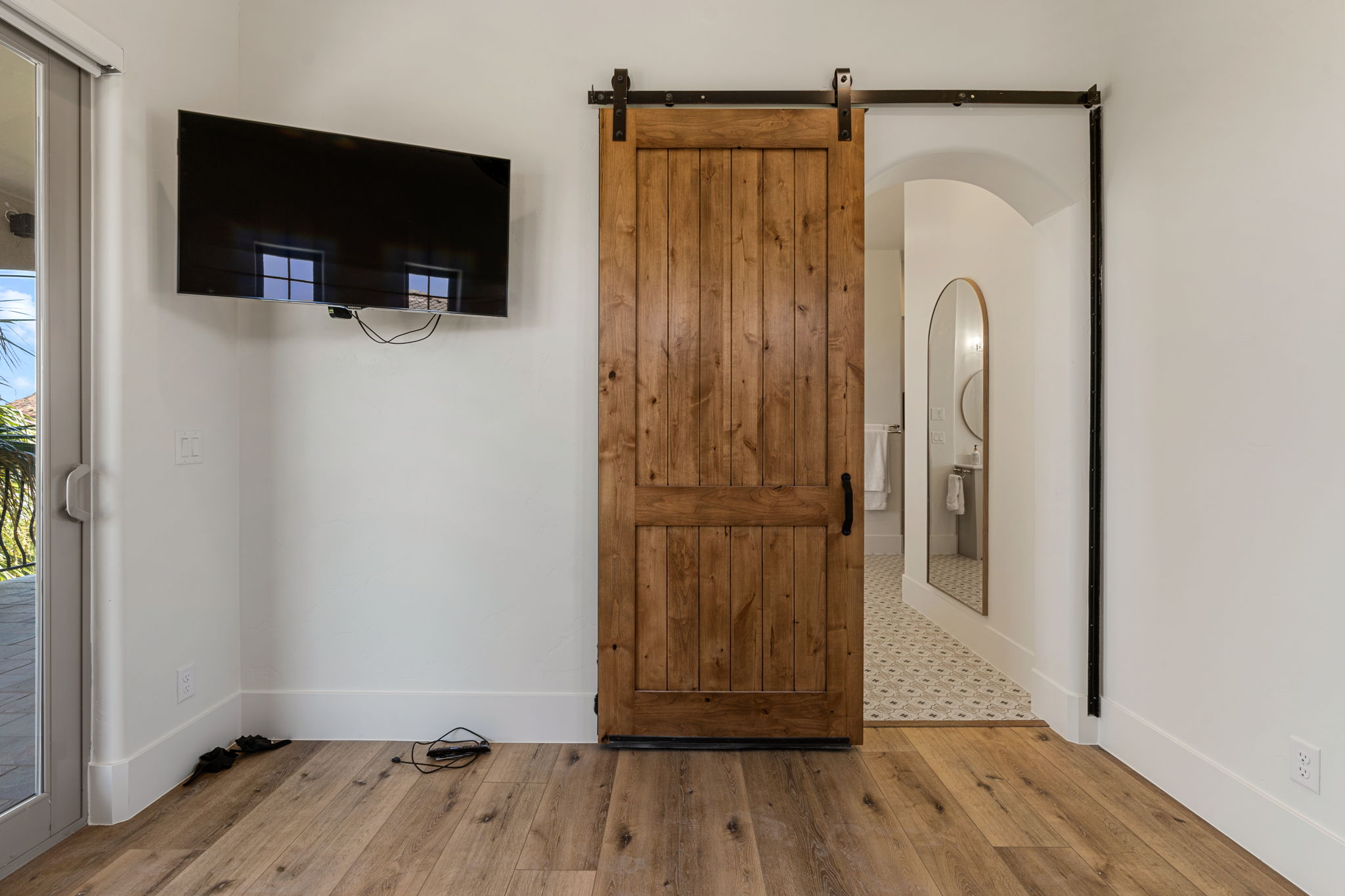 Wood-finish flooring throughout, featuring a rustic wood barn door with black hardware, and an arched entryway