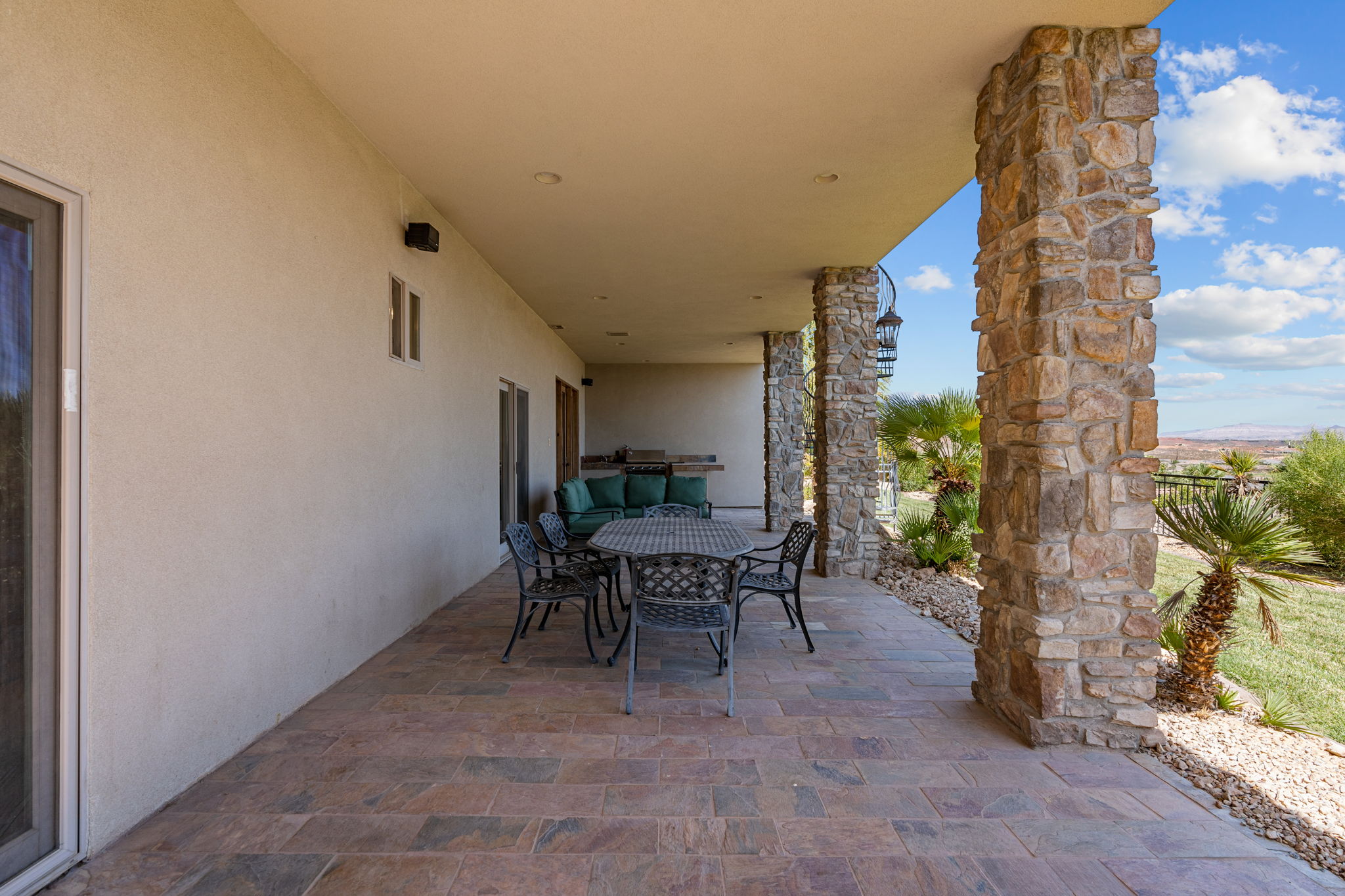 Expansive covered patio featuring large format tile flooring and robust stone columns