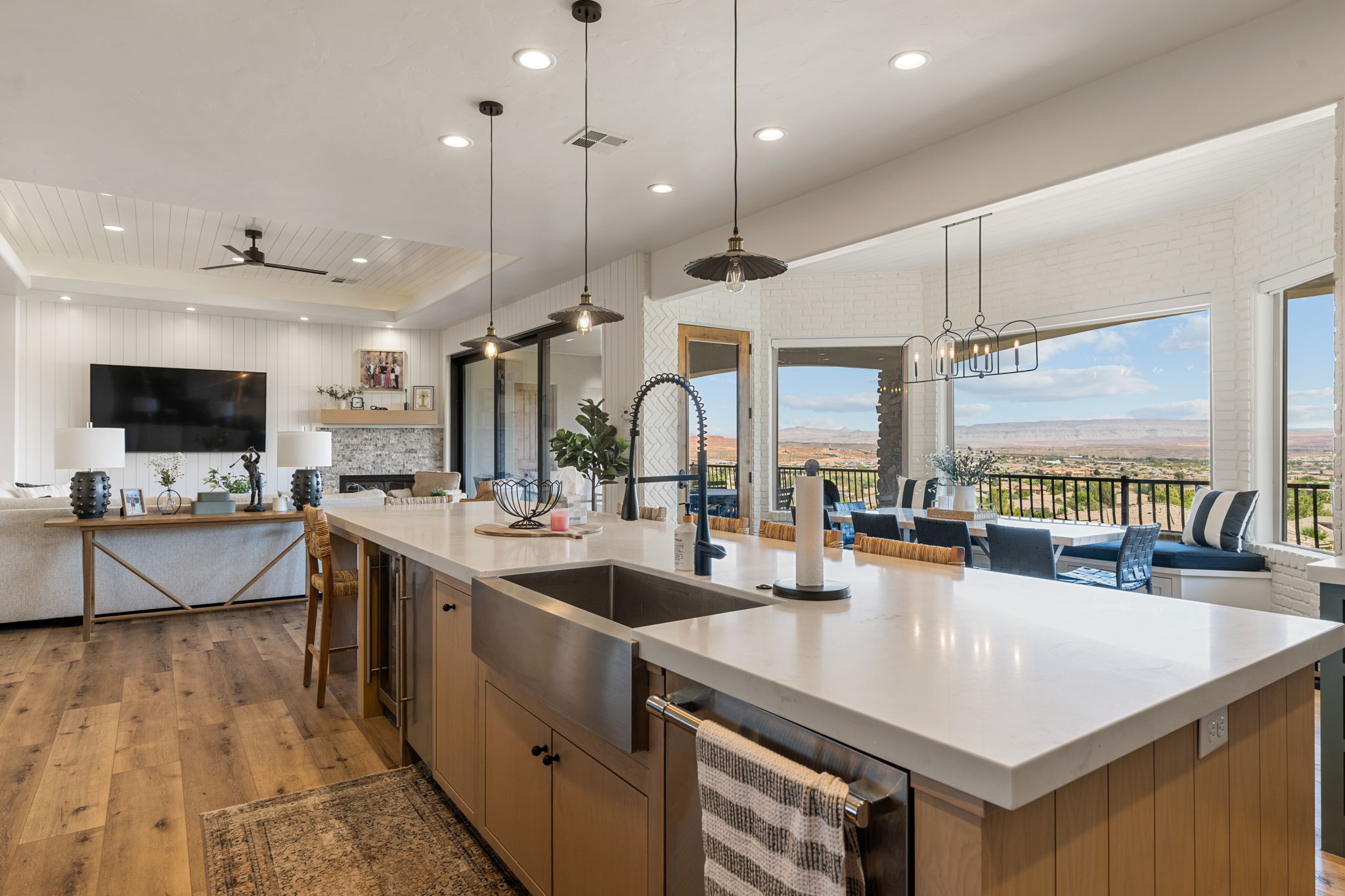 Expansive kitchen island with a stainless steel farmhouse sink, integrated dishwasher, and under-counter beverage refrigerator