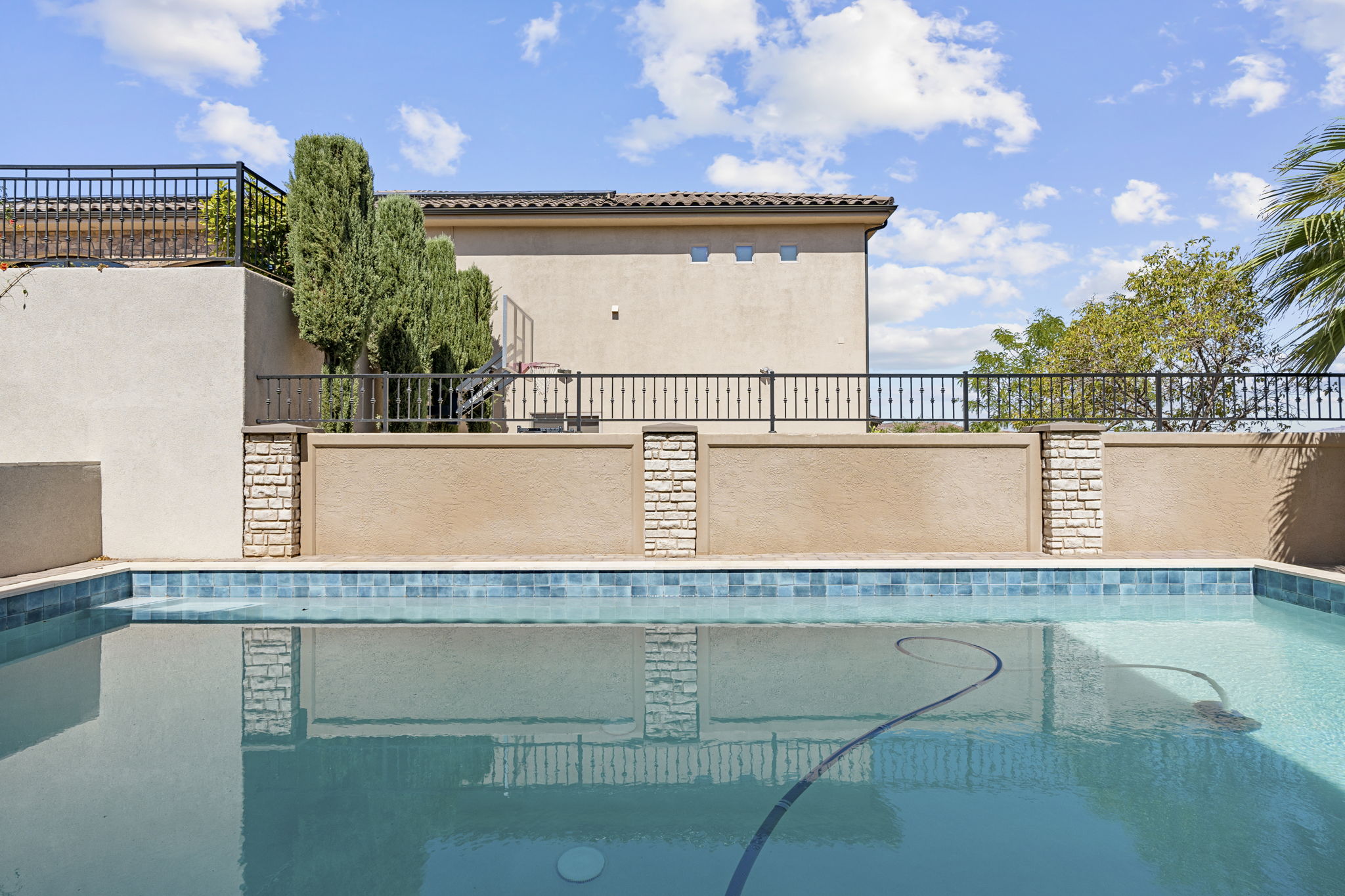 Swimming pool with blue mosaic tile border and integrated cleaning system