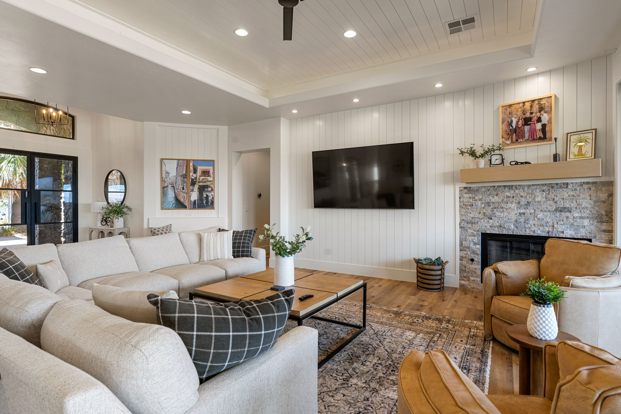 Open-concept living space featuring wood-finish flooring, a tray ceiling with recessed lighting, and white shiplap walls