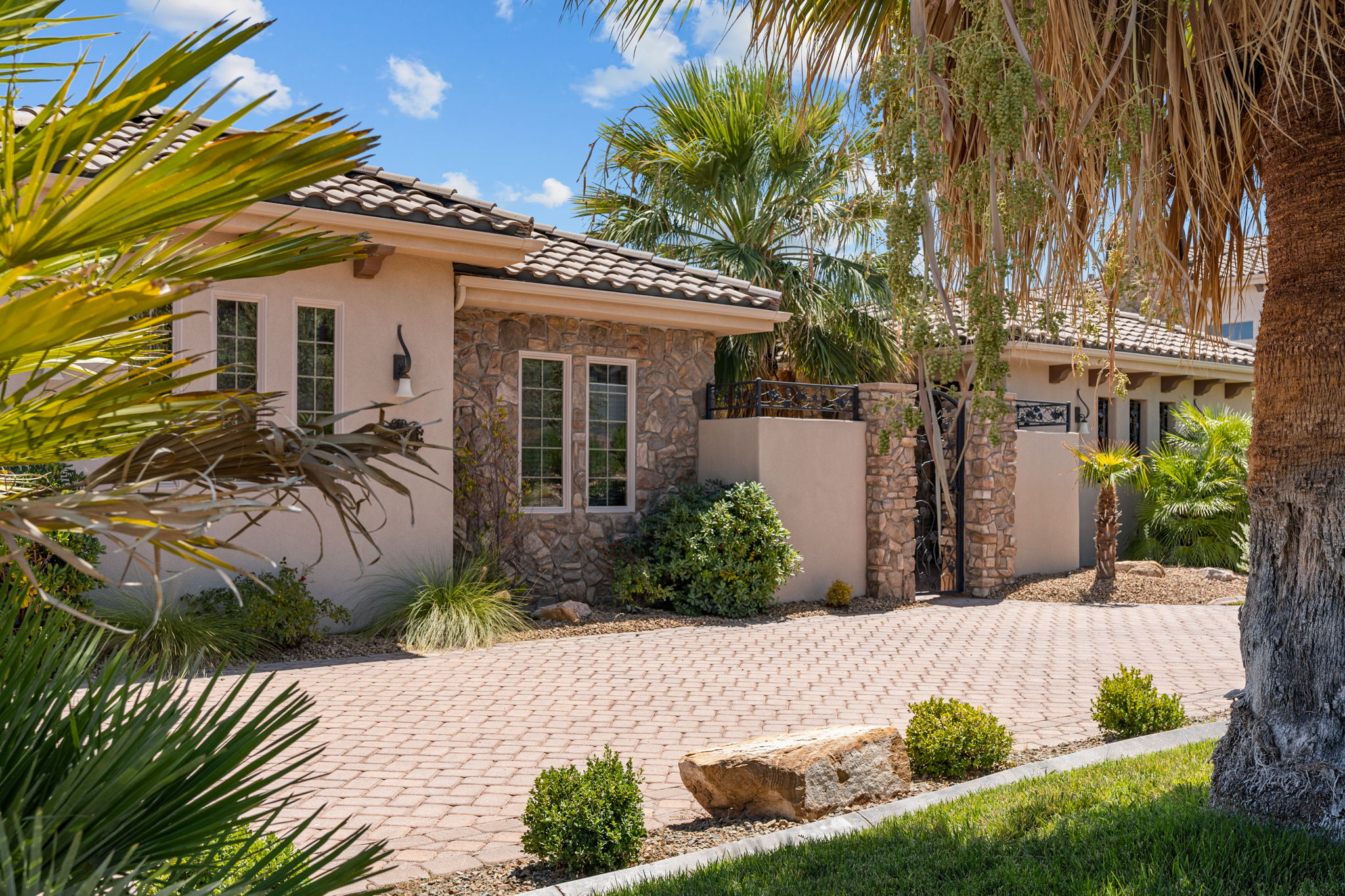 Exterior featuring a paver driveway, stone accents, stucco siding, and a tiled roof