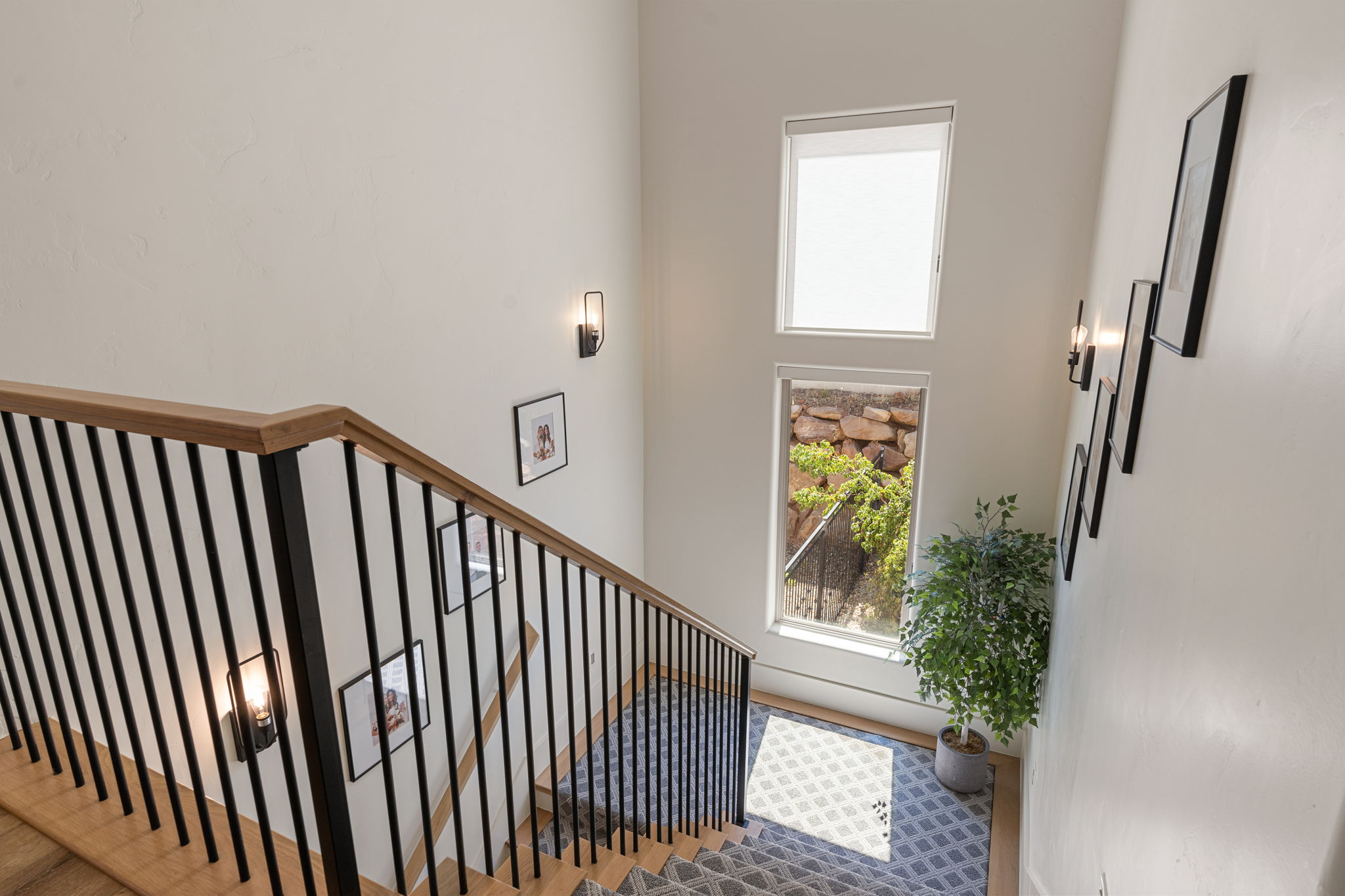 Staircase featuring wood-finish handrails, black metal balusters, and a carpeted runner