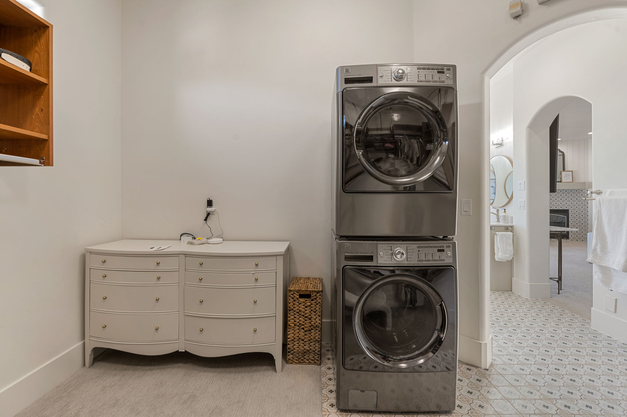 Dedicated laundry area featuring stacked stainless steel appliances and a neutral color palette