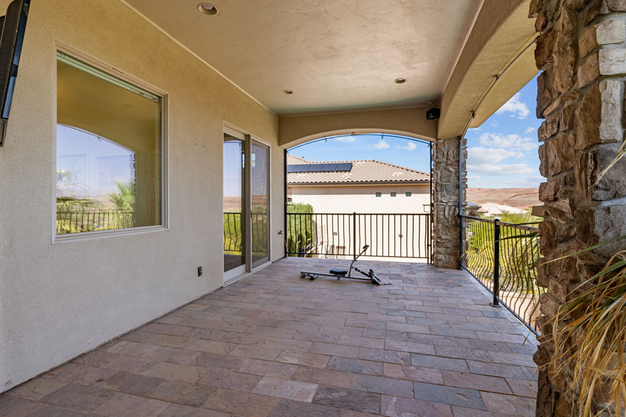 Covered patio featuring stone-finish flooring, stucco exterior, and stone-clad columns