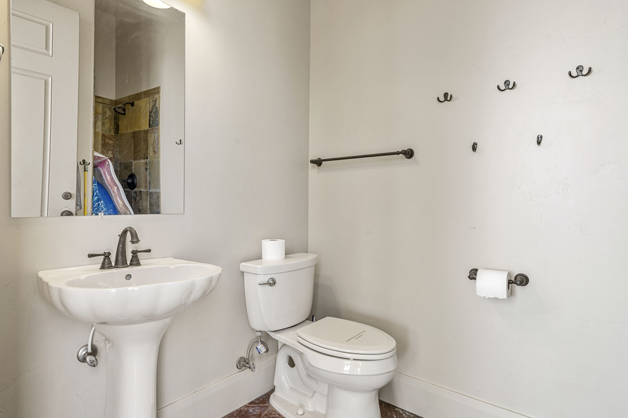Bathroom featuring a white pedestal sink with dark bronze fixtures, a white toilet, and tile flooring