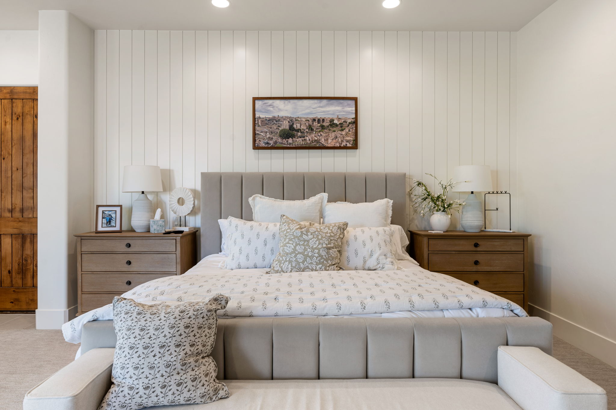 Bedroom featuring a vertical paneled accent wall, recessed lighting, and a rustic wood plank door
