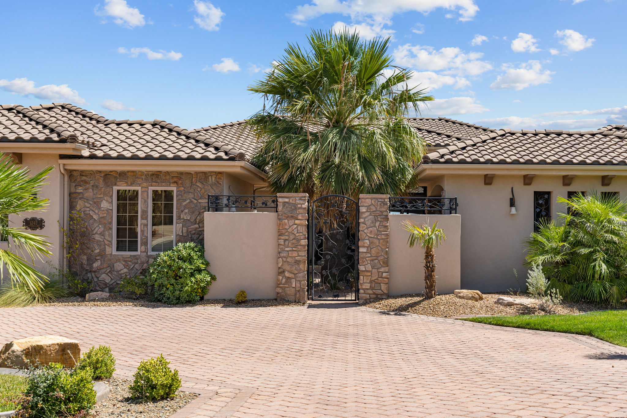 Paver driveway leading to a stucco and stone facade home with a tile roof