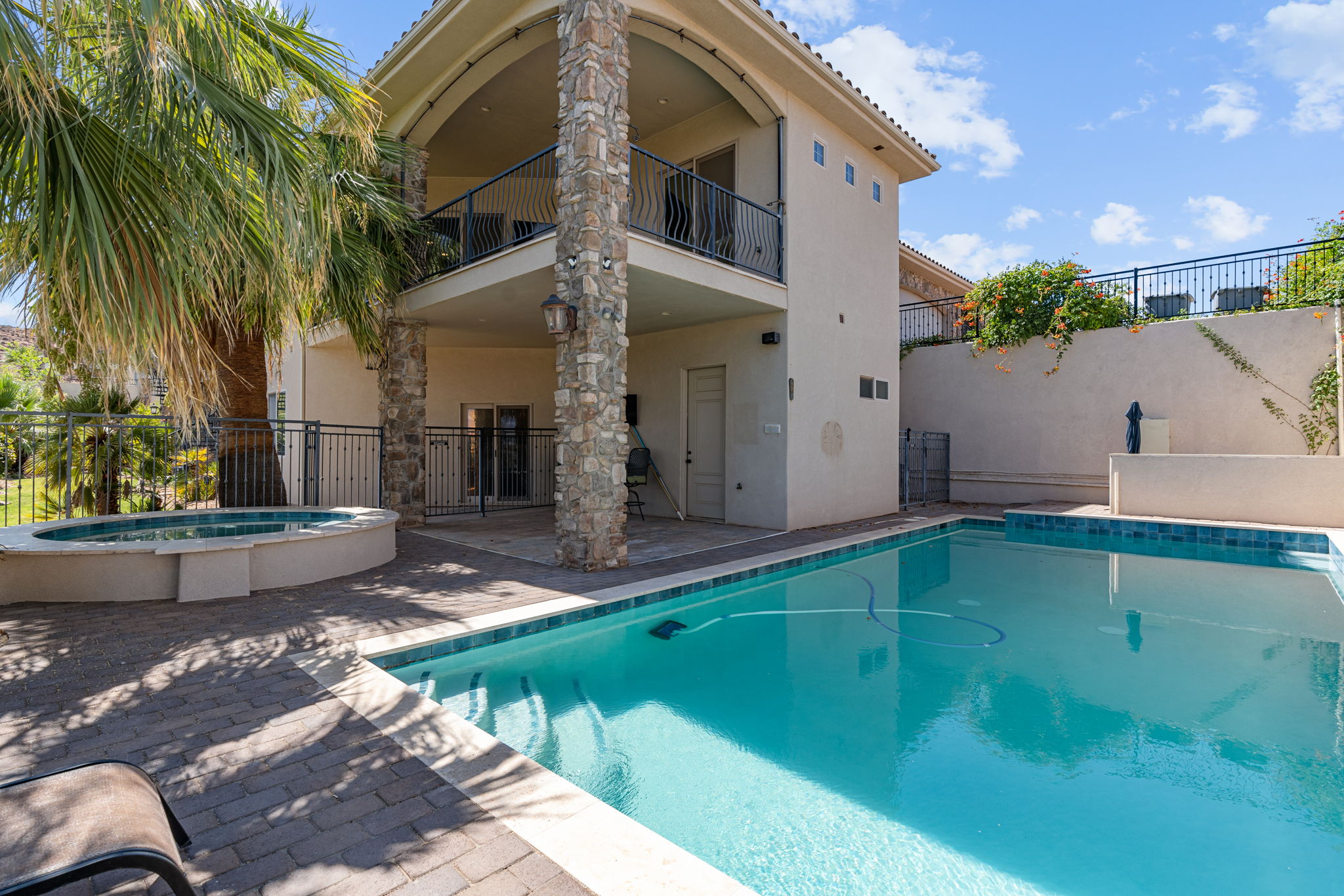 Outdoor pool with integrated spa, surrounded by stone paver decking