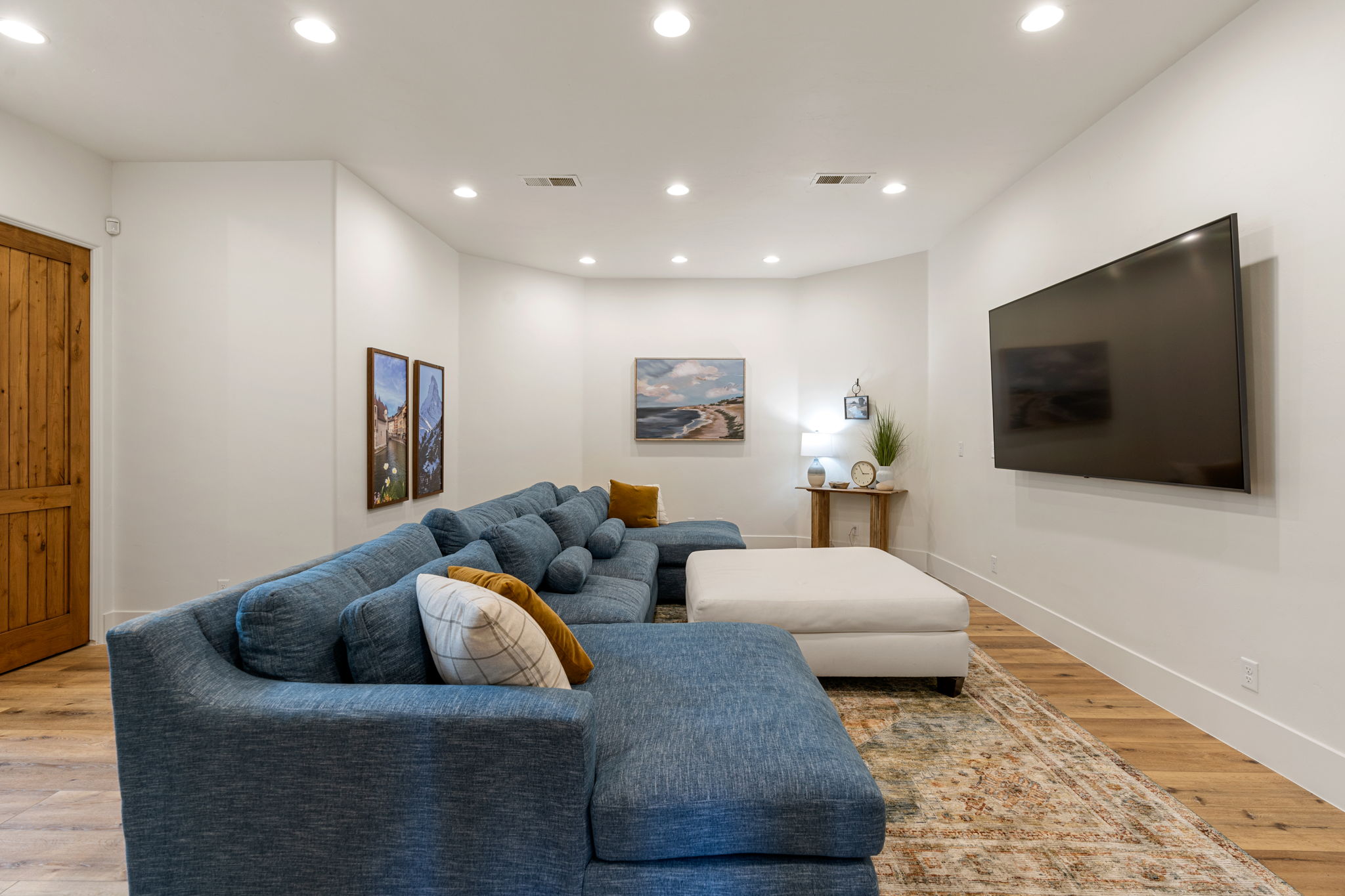 Spacious living area featuring light wood-finish flooring, recessed ceiling lighting, and a barn-style wood door