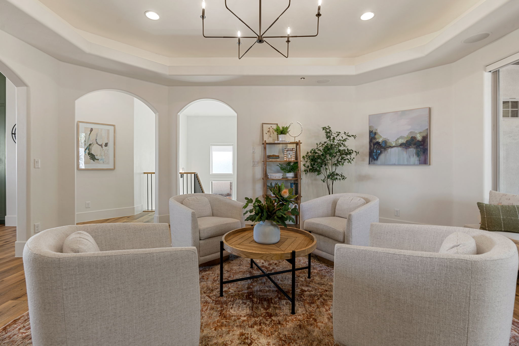 Living space featuring a tray ceiling with a linear chandelier, recessed lighting, and wood-finish flooring