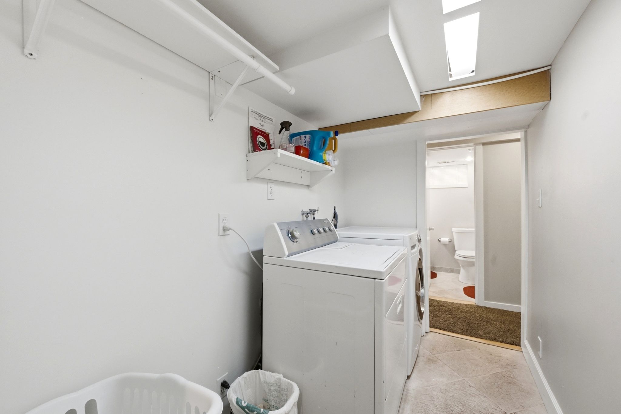 Dedicated laundry area featuring white walls, overhead shelving, and a built-in clothing rod