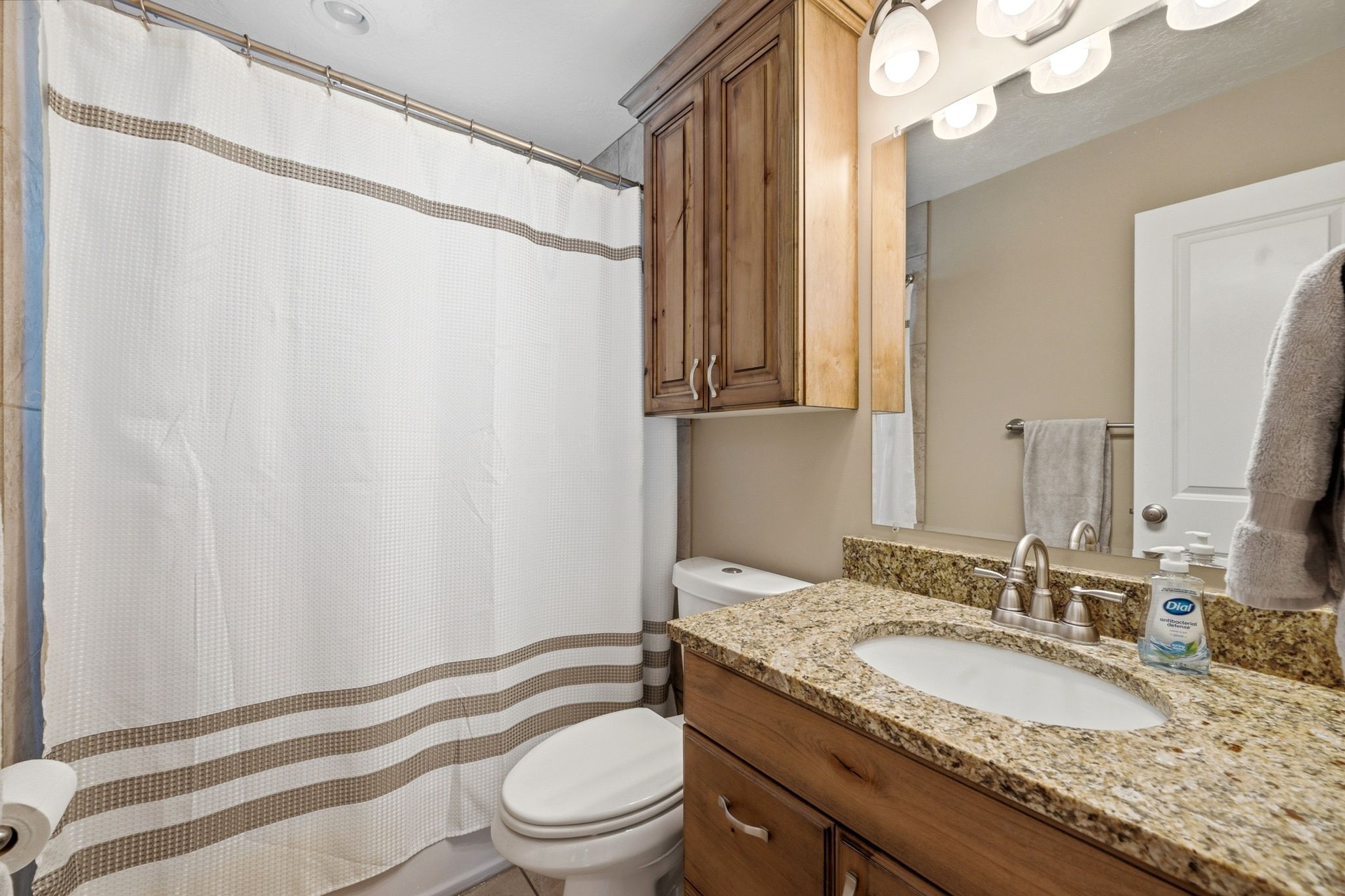 Bathroom featuring a vanity with a granite countertop, undermount sink, and brushed nickel faucet