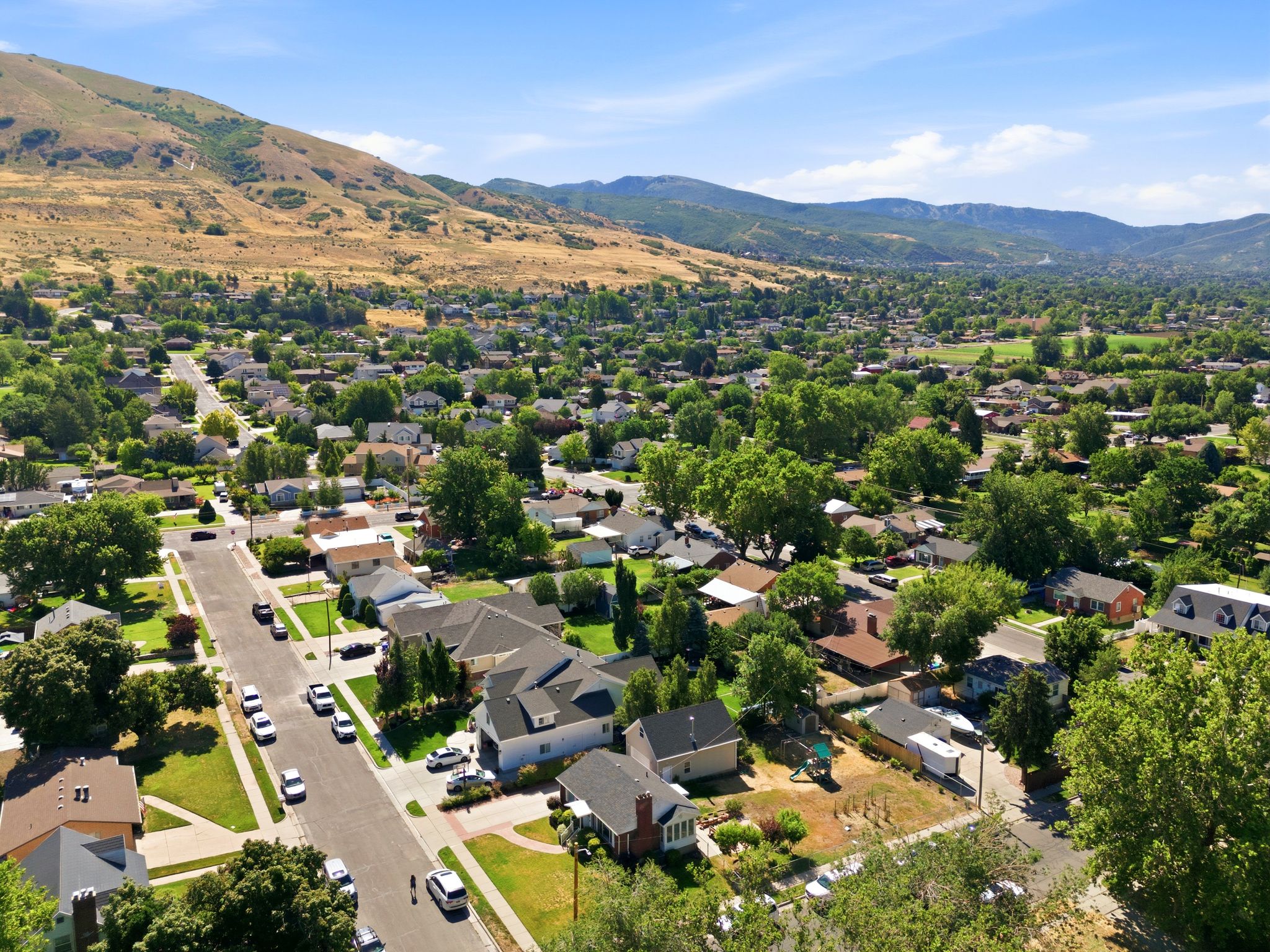 Expansive aerial perspective showcasing a residential community with mature trees and mountain backdrops