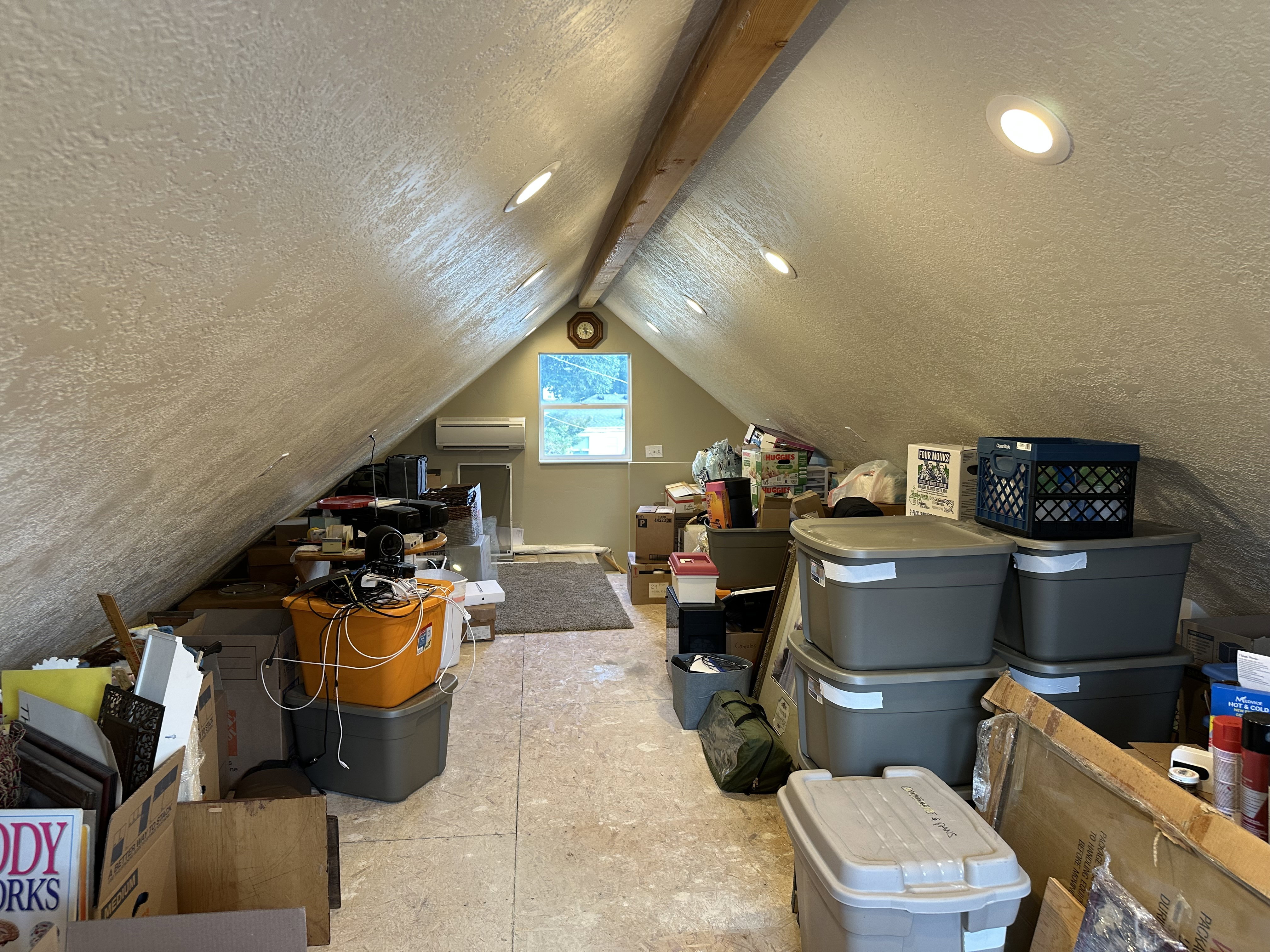 Garage loft space featuring sloped ceilings, exposed wooden beams, air-conditioning unit, and recessed lighting