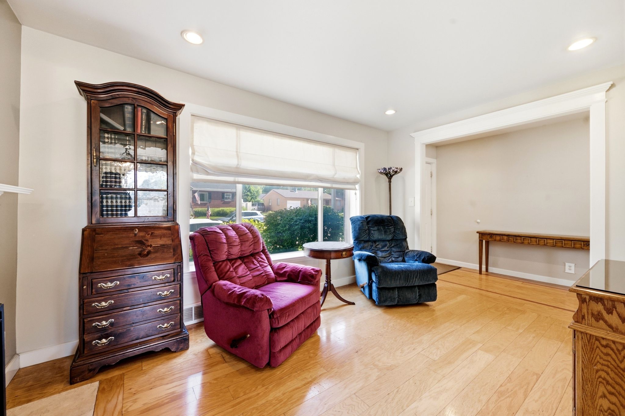 Light wood-finish flooring extends through this room, complemented by a large window with white blinds