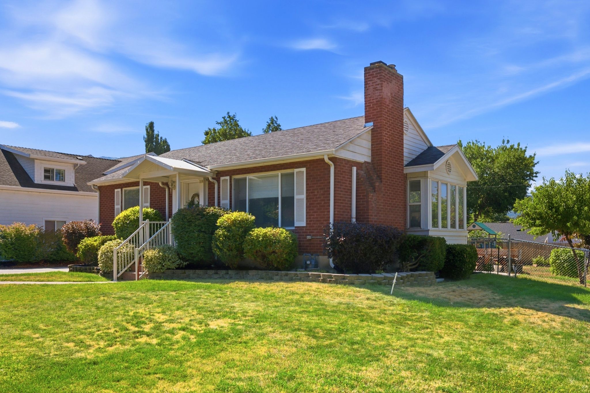 Brick exterior with white trim, a covered entry porch, and a bay window feature