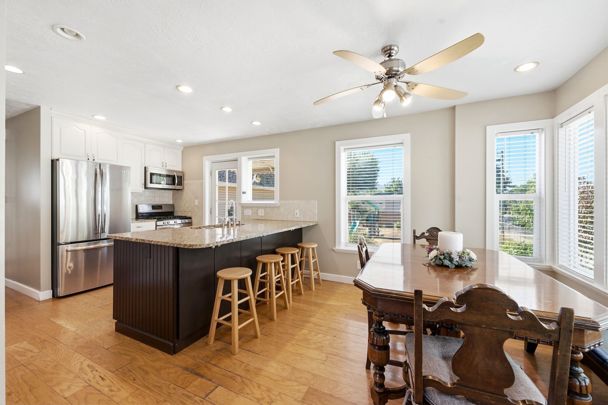 Kitchen featuring a central island with bar seating, stainless steel appliances, granite countertops, and light wood-finish flooring
