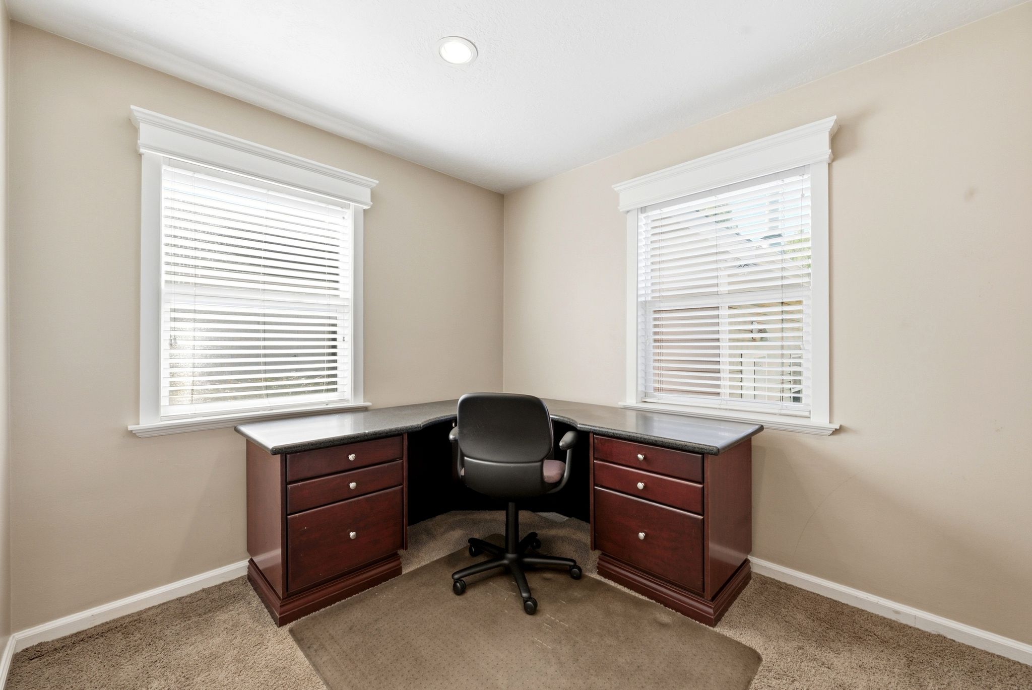 Corner room featuring two windows with white blinds and ornate window trim