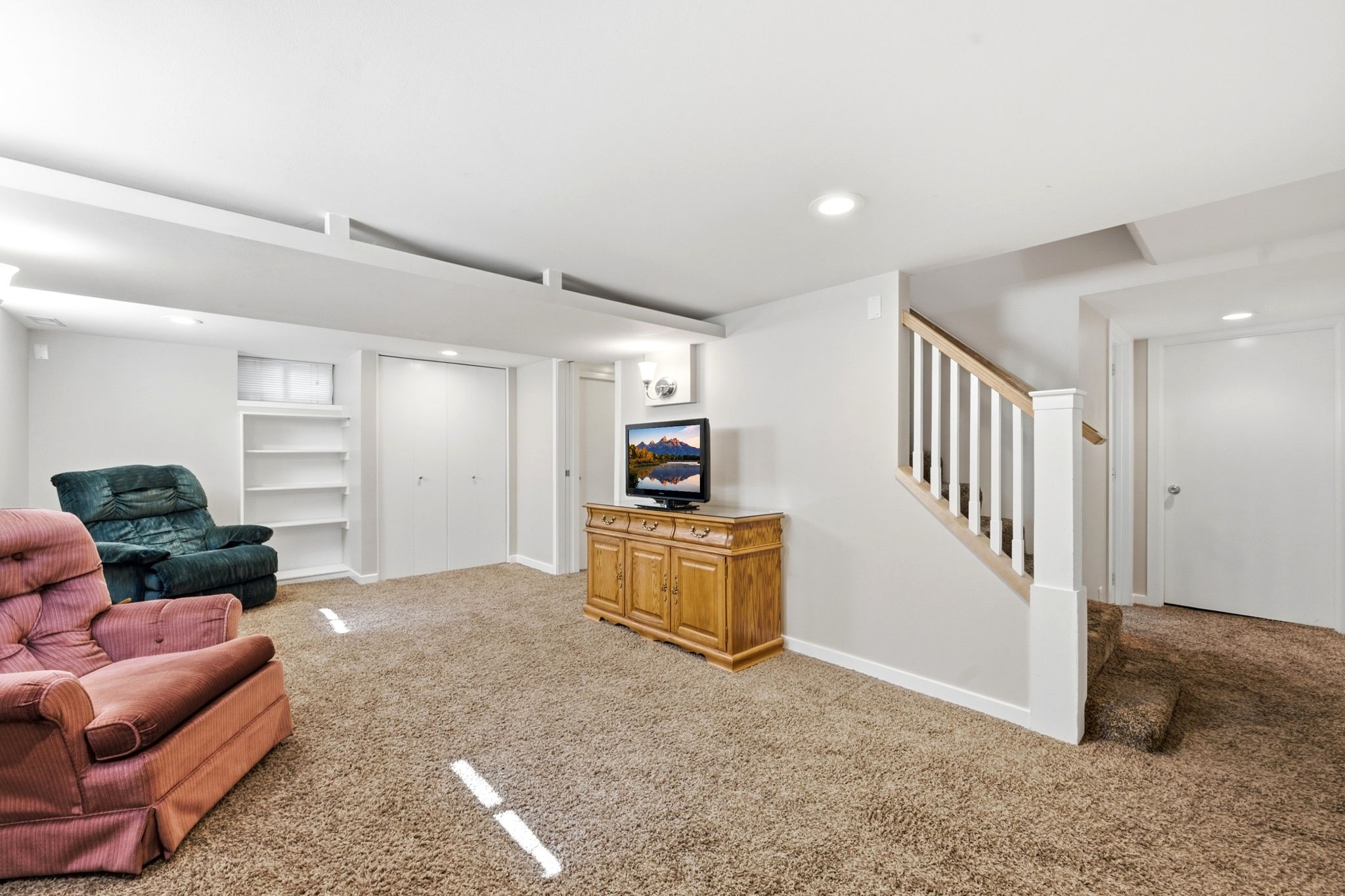 Spacious carpeted room featuring white walls and recessed lighting