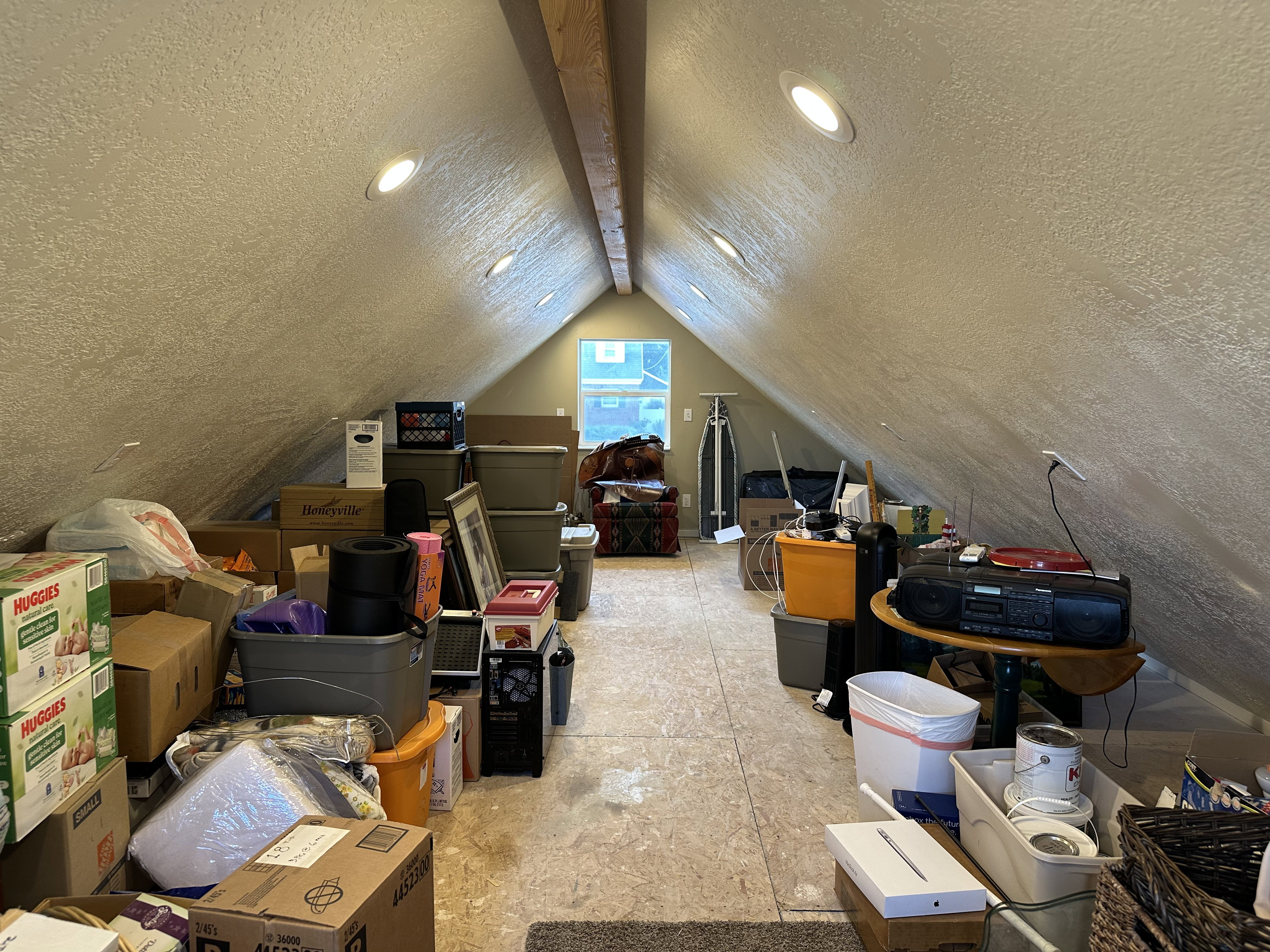 Garage loft space featuring sloped ceilings, recessed lighting, exposed ceiling beam, light-toned flooring, and a window providing natural light