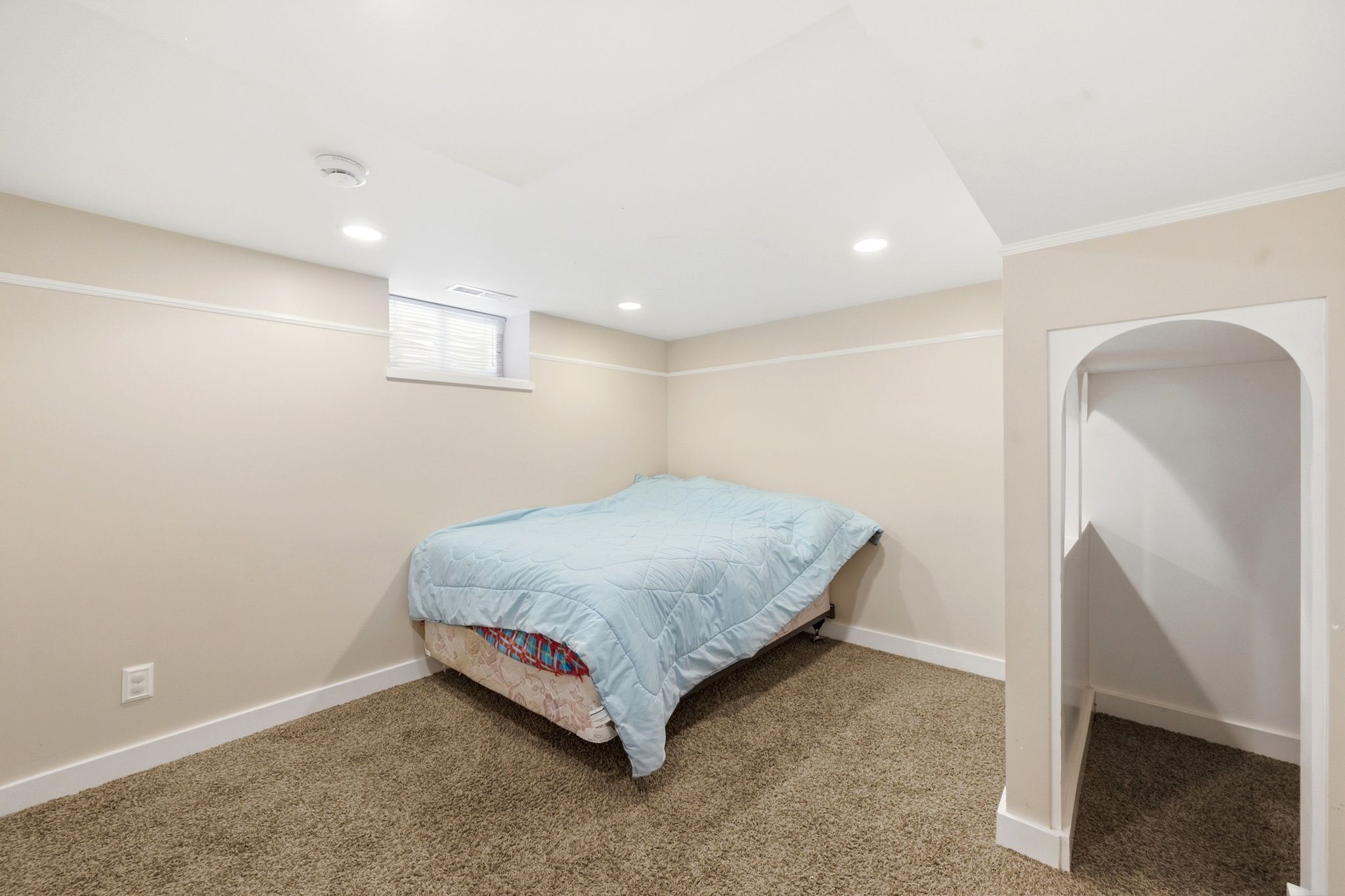 Carpeted room featuring a window, recessed lighting, and an arched alcove